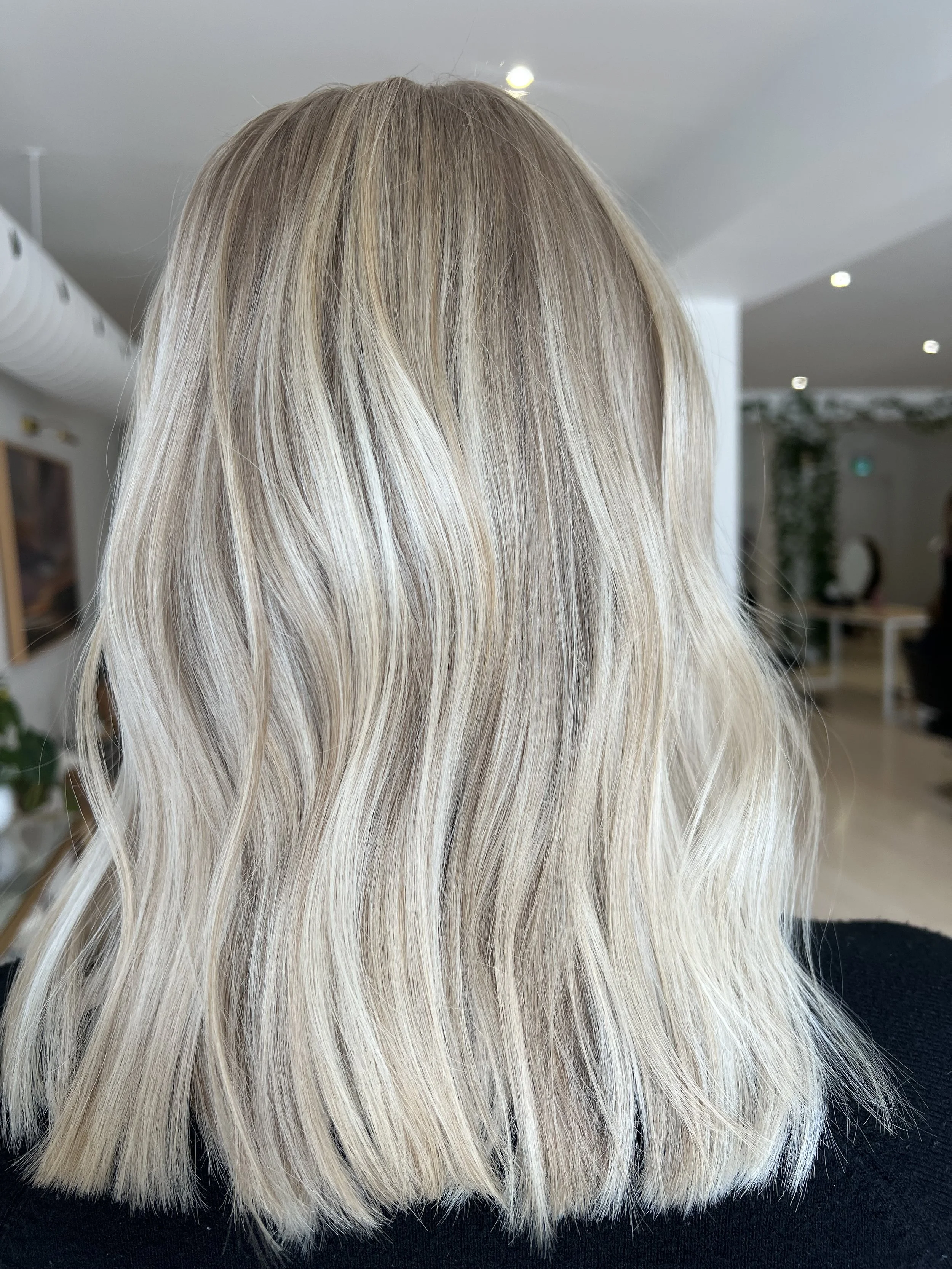 Close-up of long, blonde, layered hair with light highlights in a salon setting.