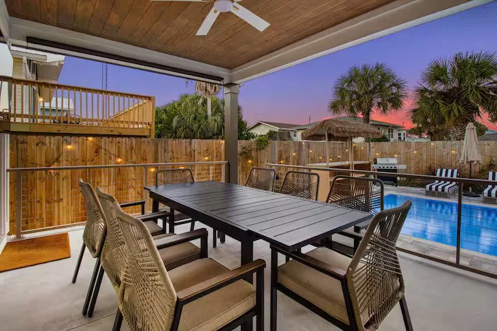Outdoor dining area with string lights at twilight near pool in Panama City Beach rental