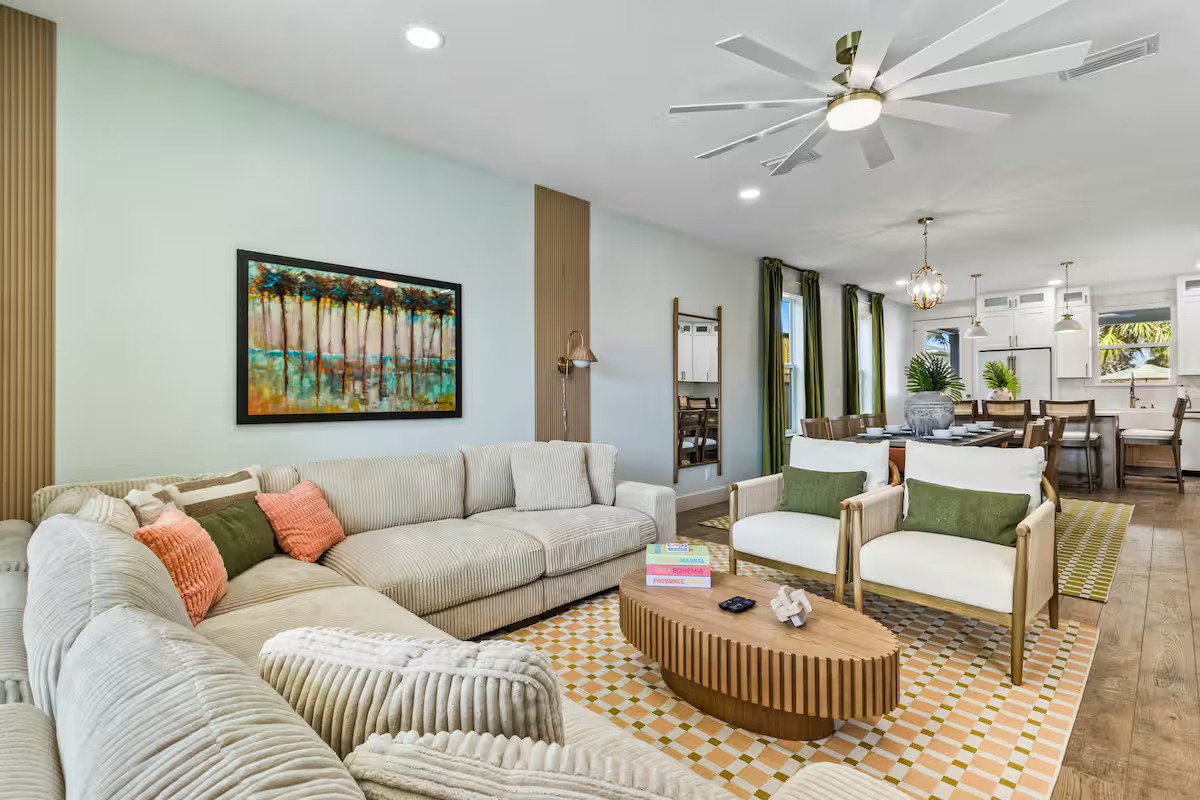 Open living room, dining, and kitchen with tropical design, oversized couch, and luxury finishes