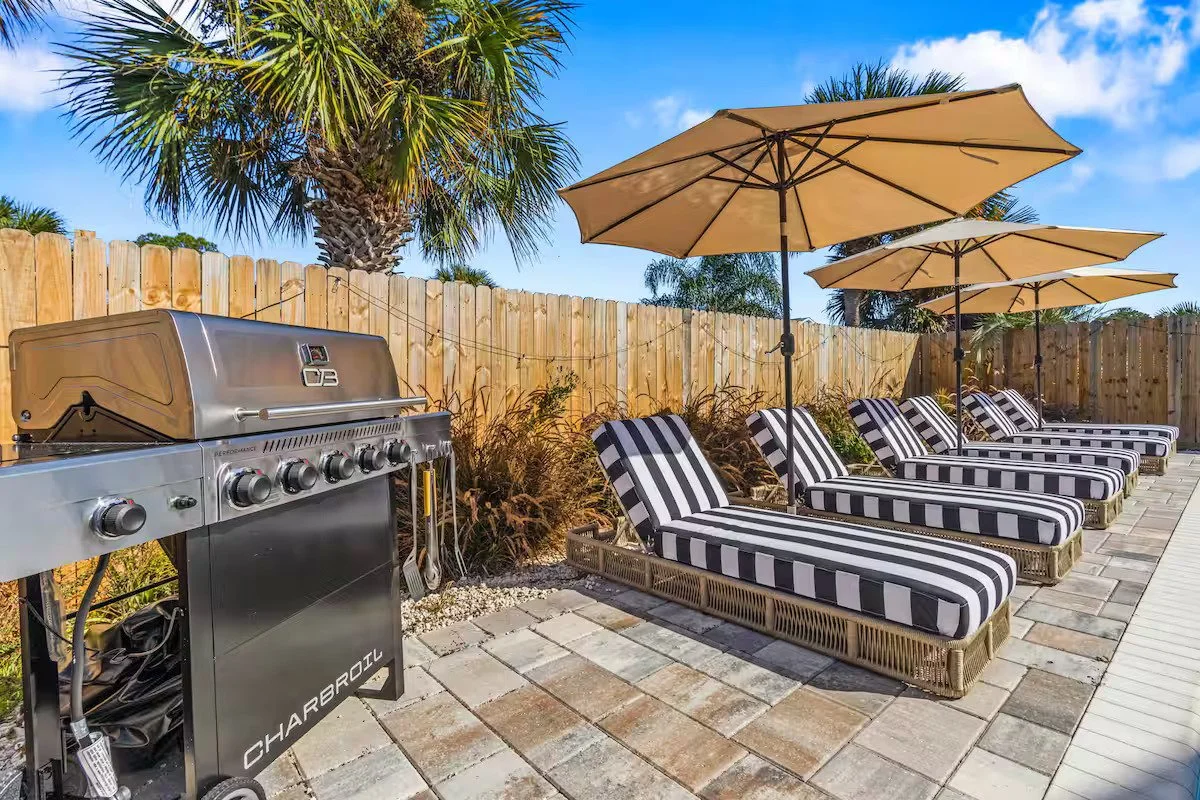 Private pool area with grill, loungers, and umbrellas at Panama City Beach vacation rental