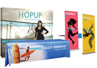 A promotional display with a woman standing behind it, advertising hop technology, fully printed graphics, and a colorful yellow and pink sign with a black umbrella and a person holding a yellow plant.