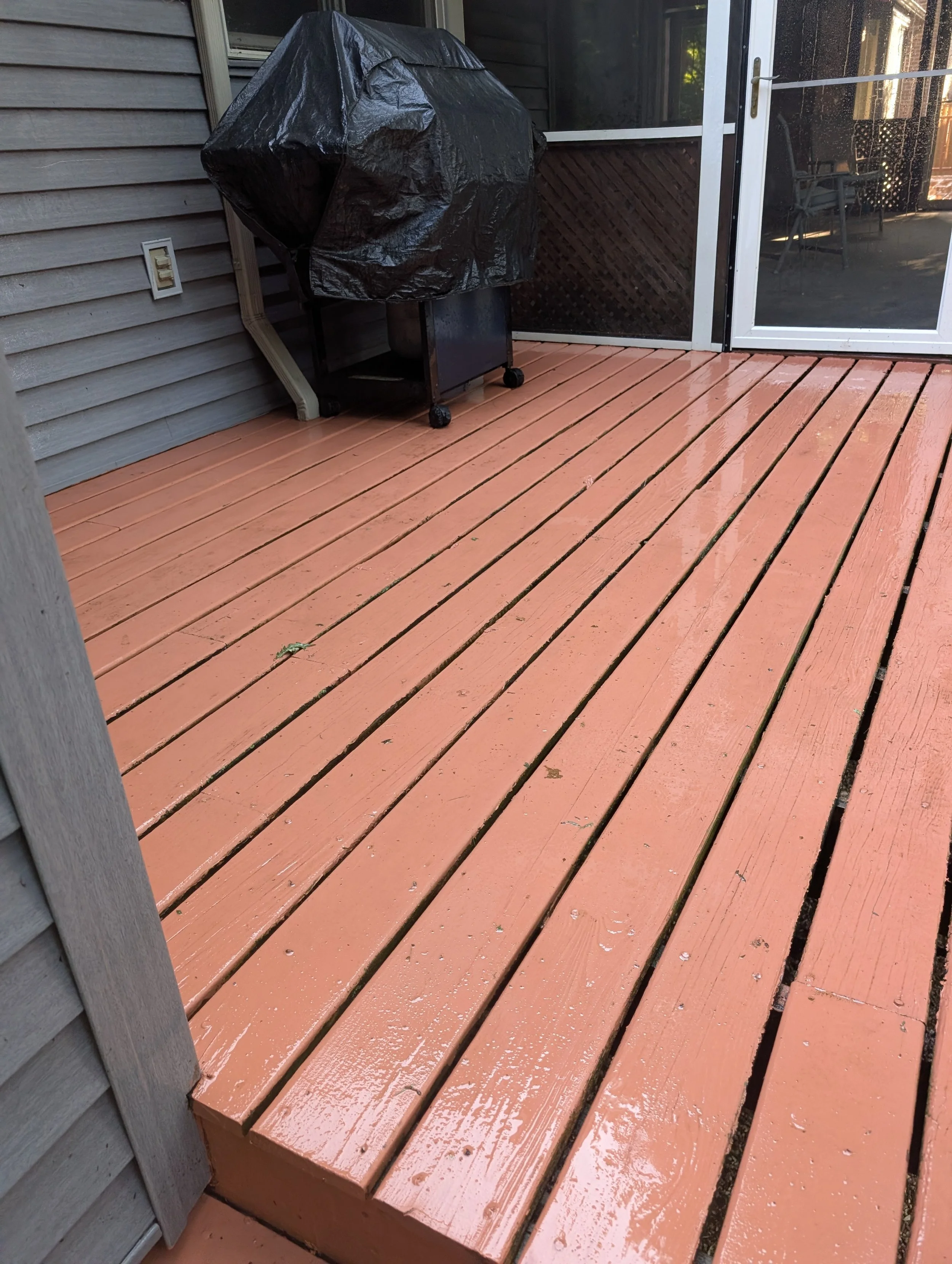 A freshly pressure washed red painted deck.