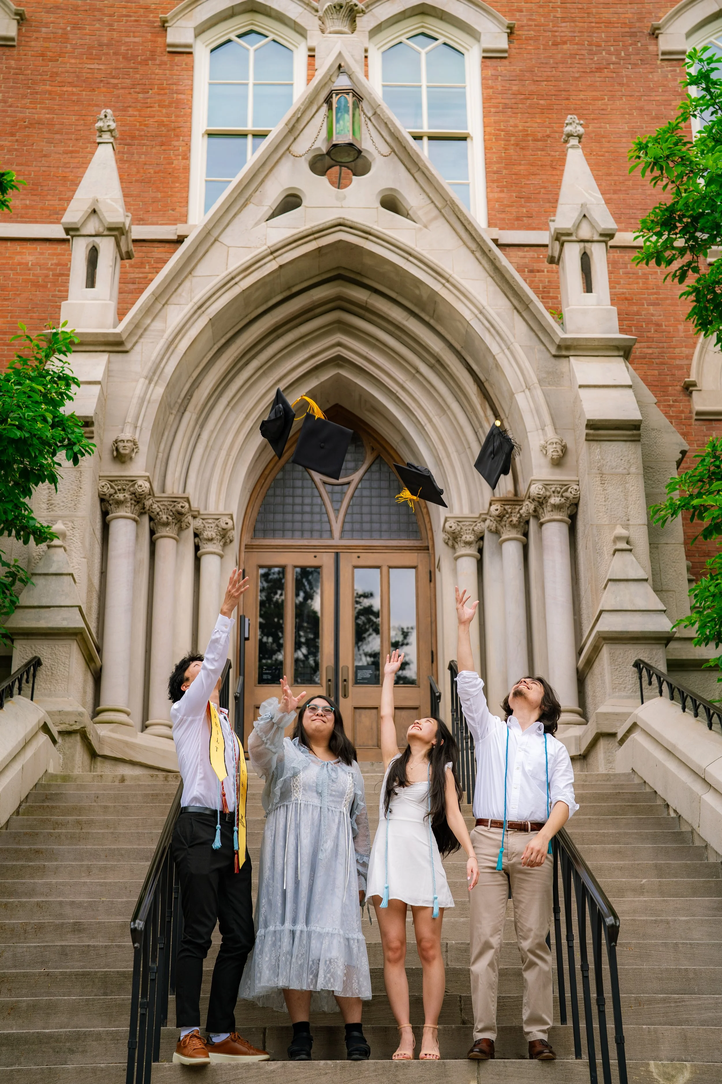 Grad students celebrating graduation outside a university building as they toss caps in the air.