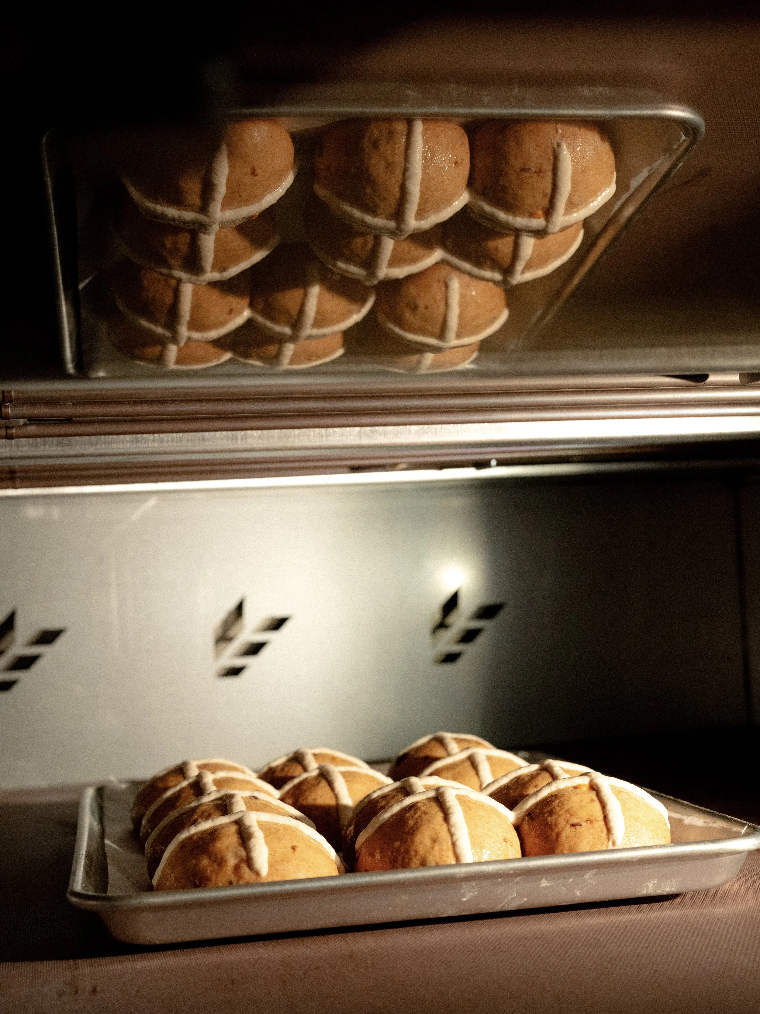 Tray of decorated cookies with a white icing cross design on top, placed on a metal rack.
