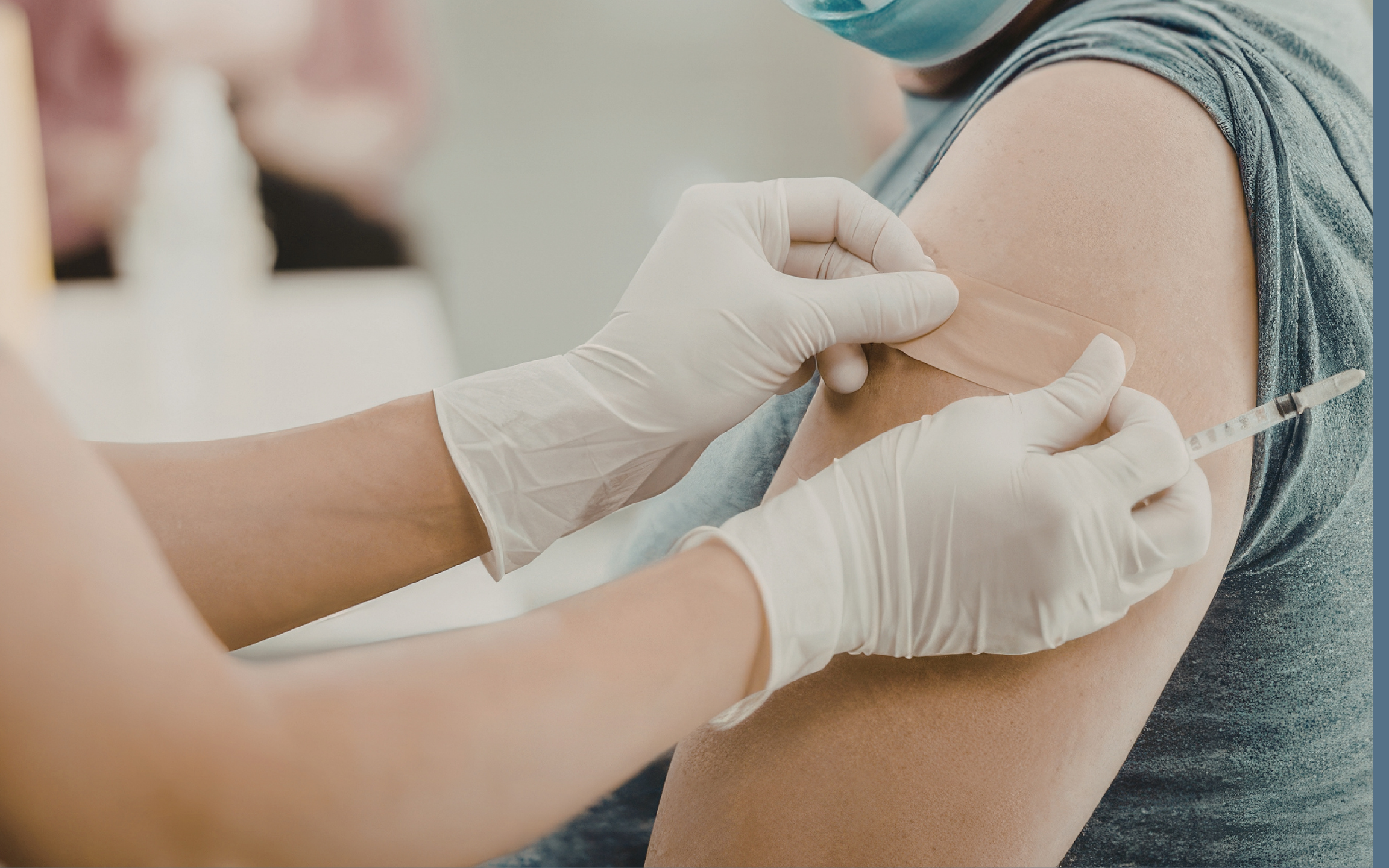 Una persona recibiendo una vacuna en el brazo, con guantes médicos puestos, en un ambiente clínico.