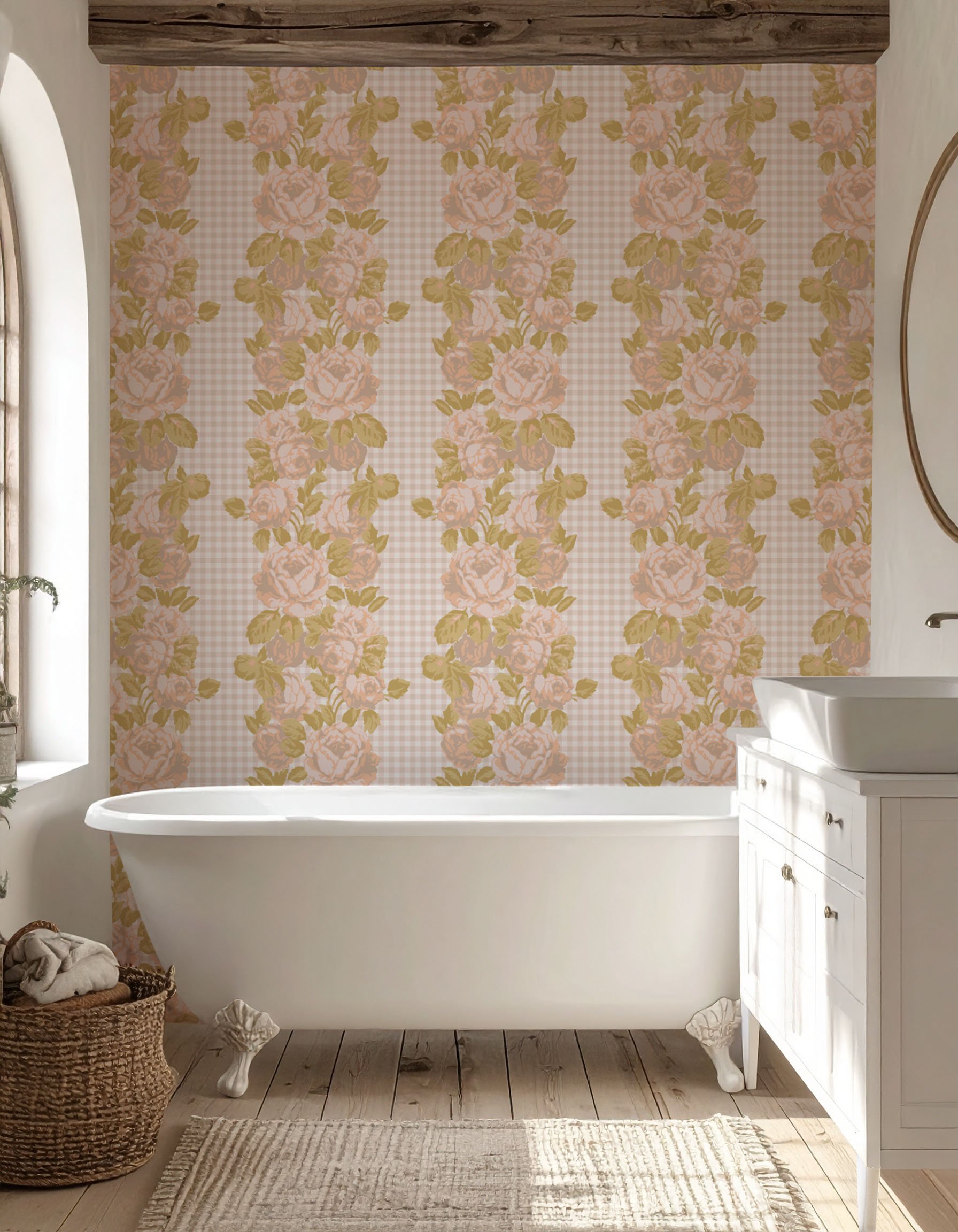 A bathroom with a vintage floral wallpaper featuring pink roses and green leaves, a white freestanding bathtub, a woven basket with towels, a white vanity with a vessel sink, a floor rug, and a window with sunlight streaming in.