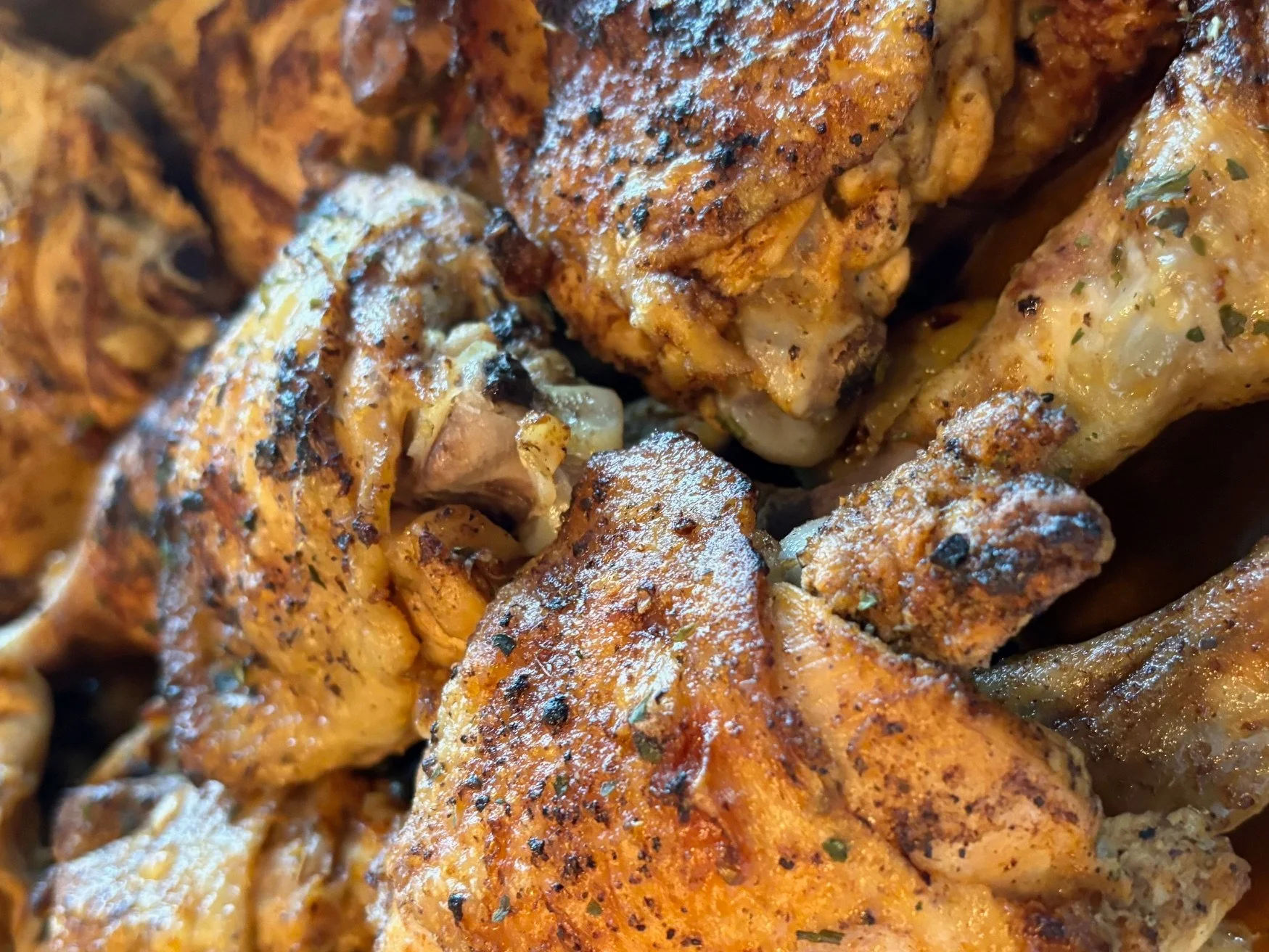 Close-up of seasoned and cooked chicken pieces with herbs and spices.