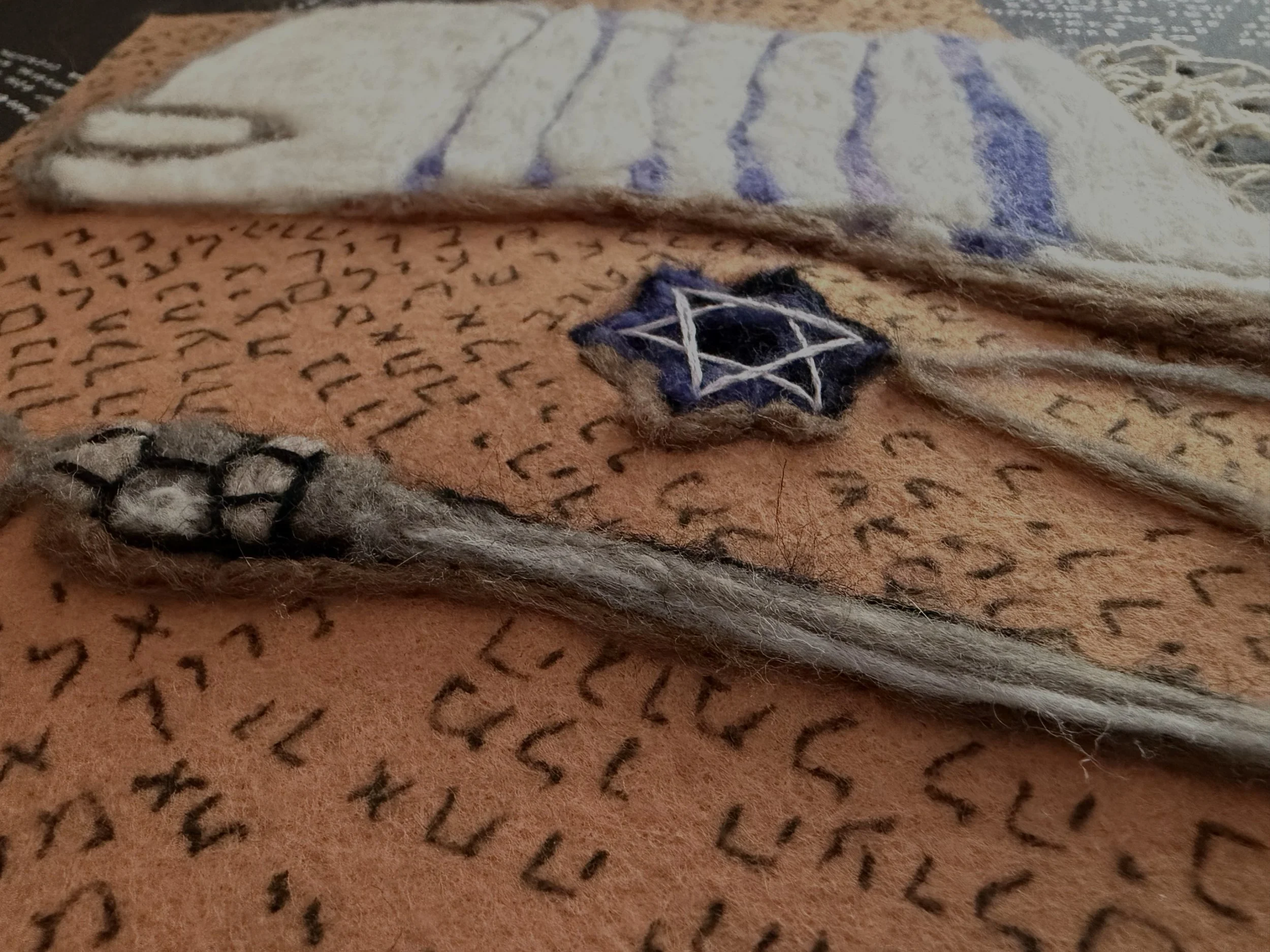 A close-up of a textured fabric with a star-shaped patch, placed on a patterned surface with black, Hebrew text.