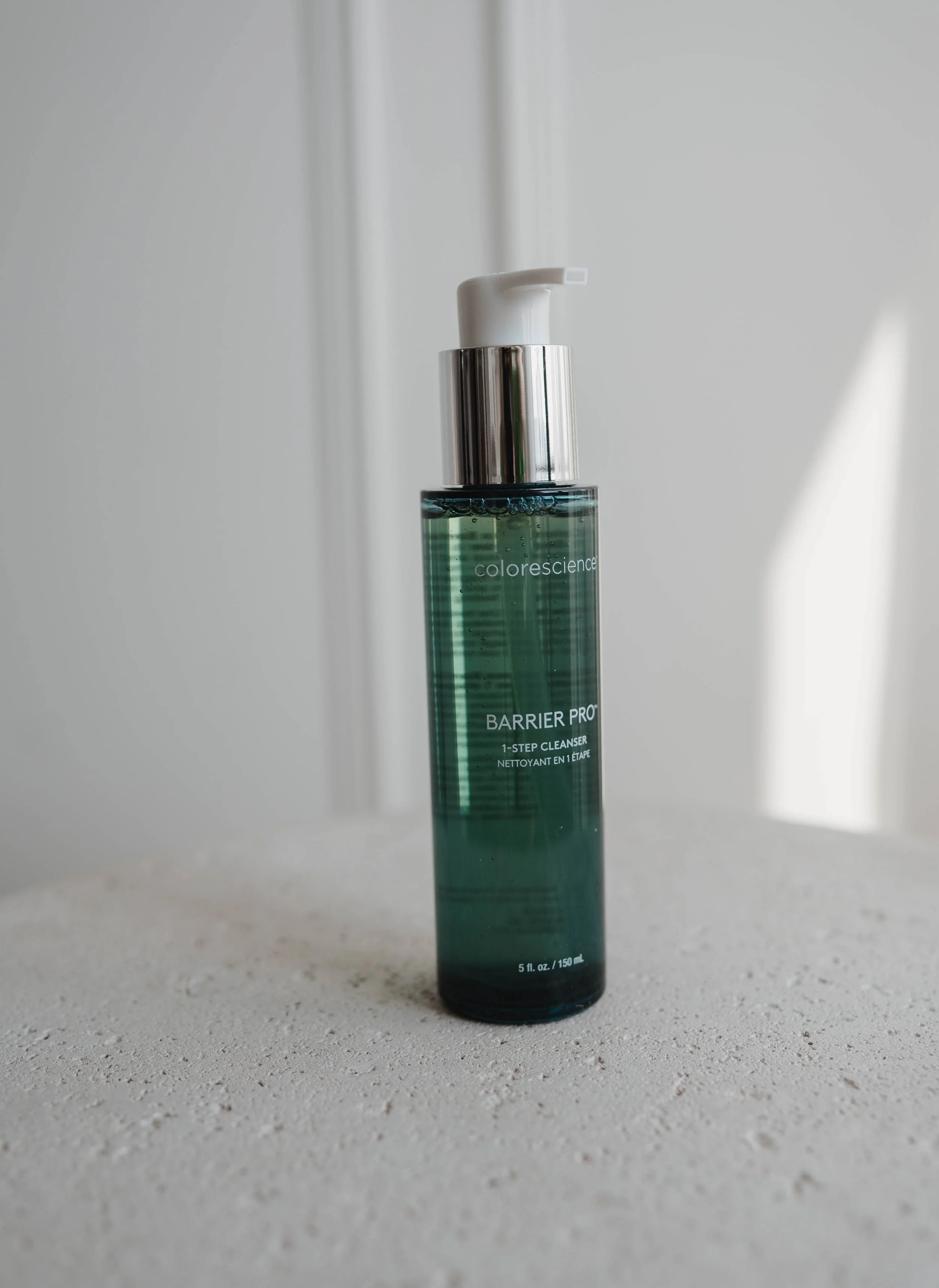A bottle of Colorescience Barrier Pro 1-Step Cleanser on a textured surface with a plain white background.