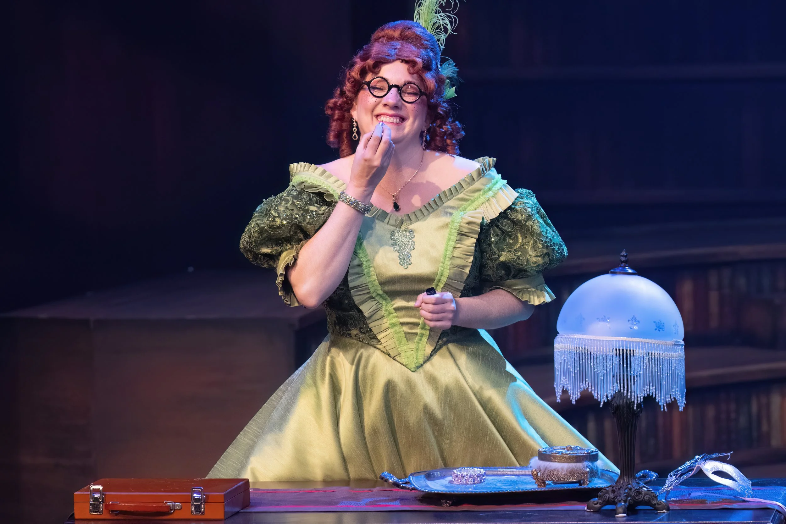 The comic highlight of the show is Sara Burke doing a wildly funny comic turn as Charlotte, the less favored of Ella’s stepsisters. In red wig, spectacles, and lime, green gown, she squalls, complains, does adorable prattfalls throughout the action. 