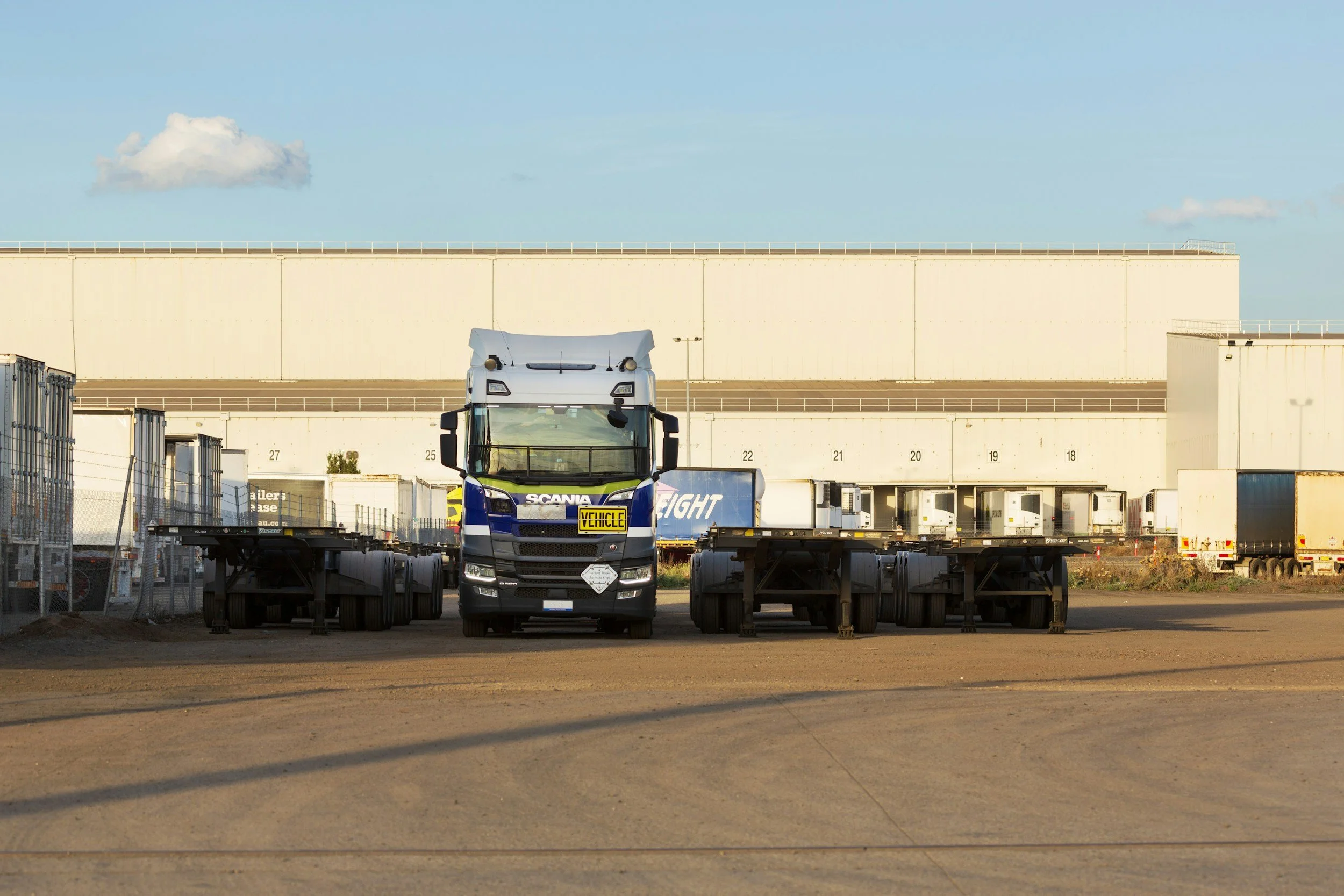 Semi trucks lined up at a warehouse loading dock at sunrise