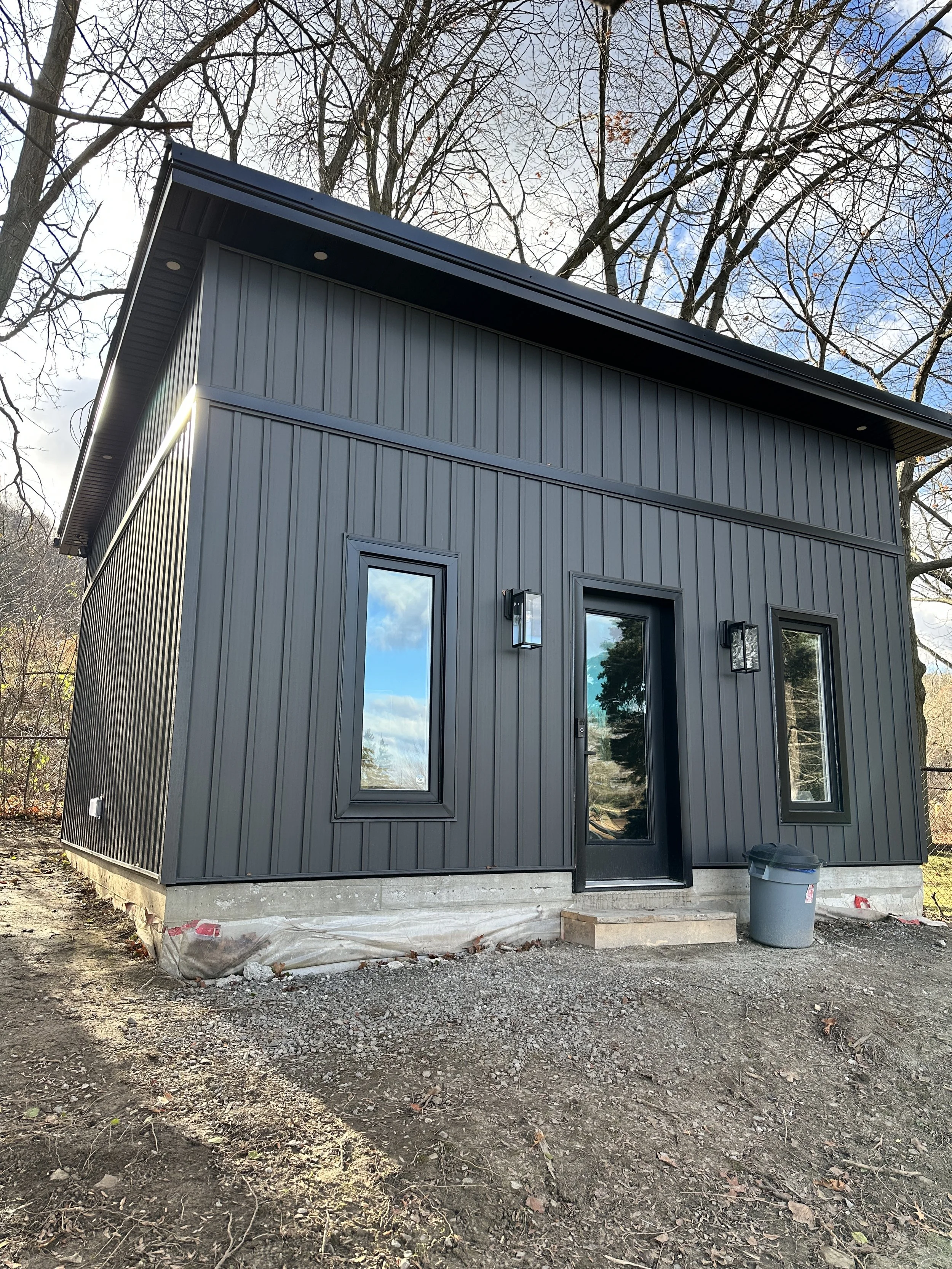 Newly built small black metal home with a concrete foundation, three steps to the front door.