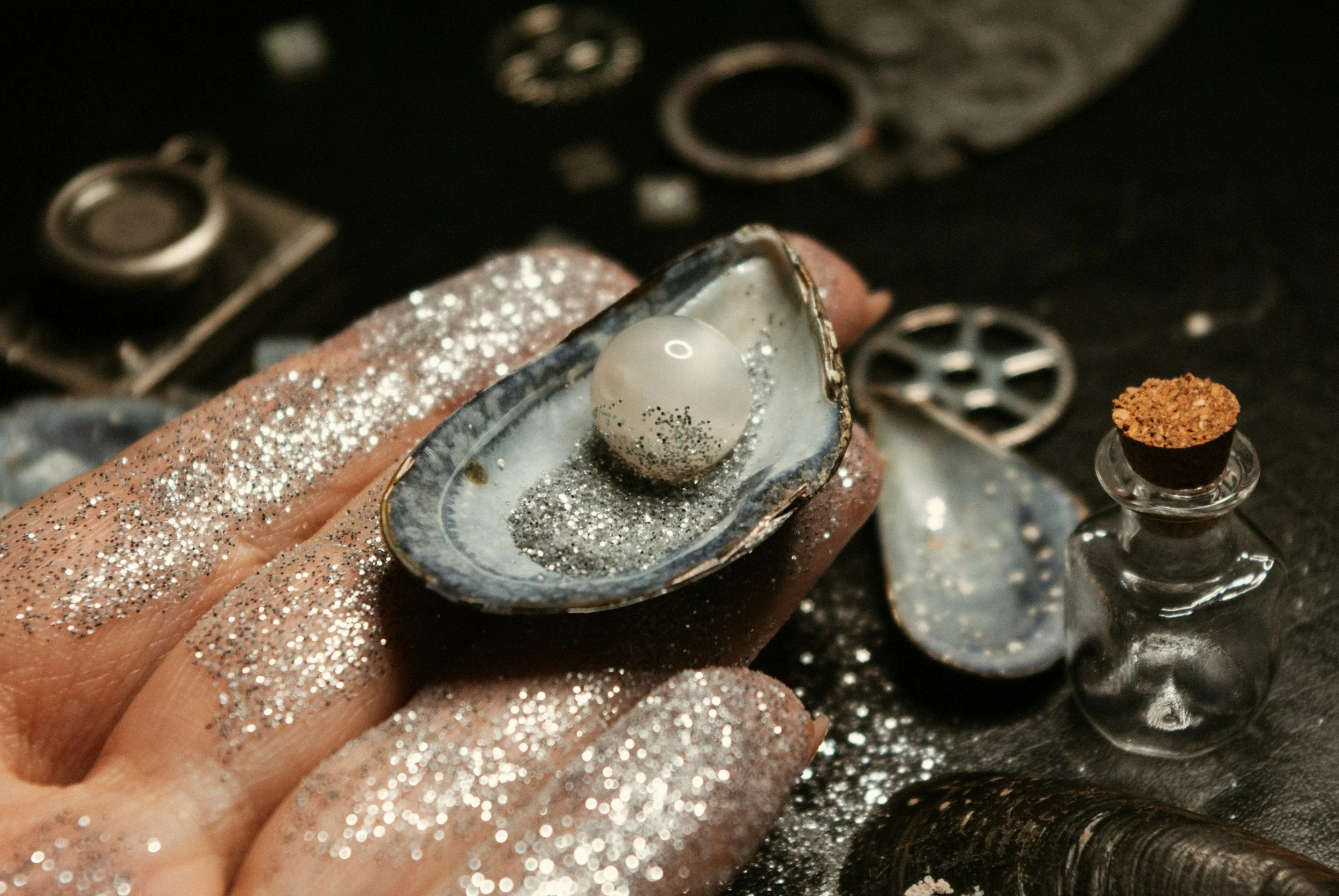 Glittery hand holding shell with pearl
