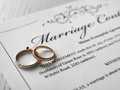 Close-up of two gold wedding rings resting on a marriage certificate document.
