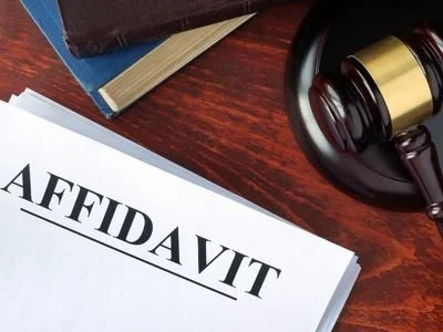 Close-up of a legal document labeled 'AFFIDAVIT' on a wooden desk with a gavel, books, and papers nearby.