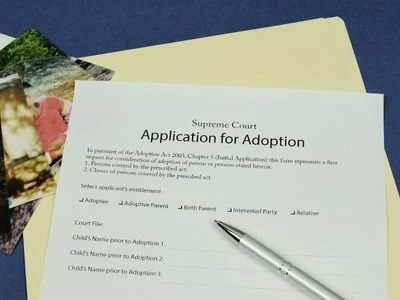 Application for adoption form on a table with a pen and documents.