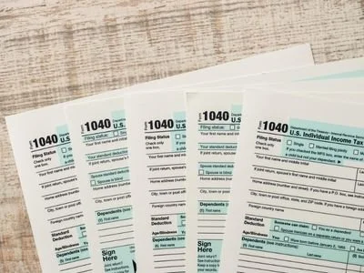 Stack of IRS Form 1040 tax documents on a wooden surface.