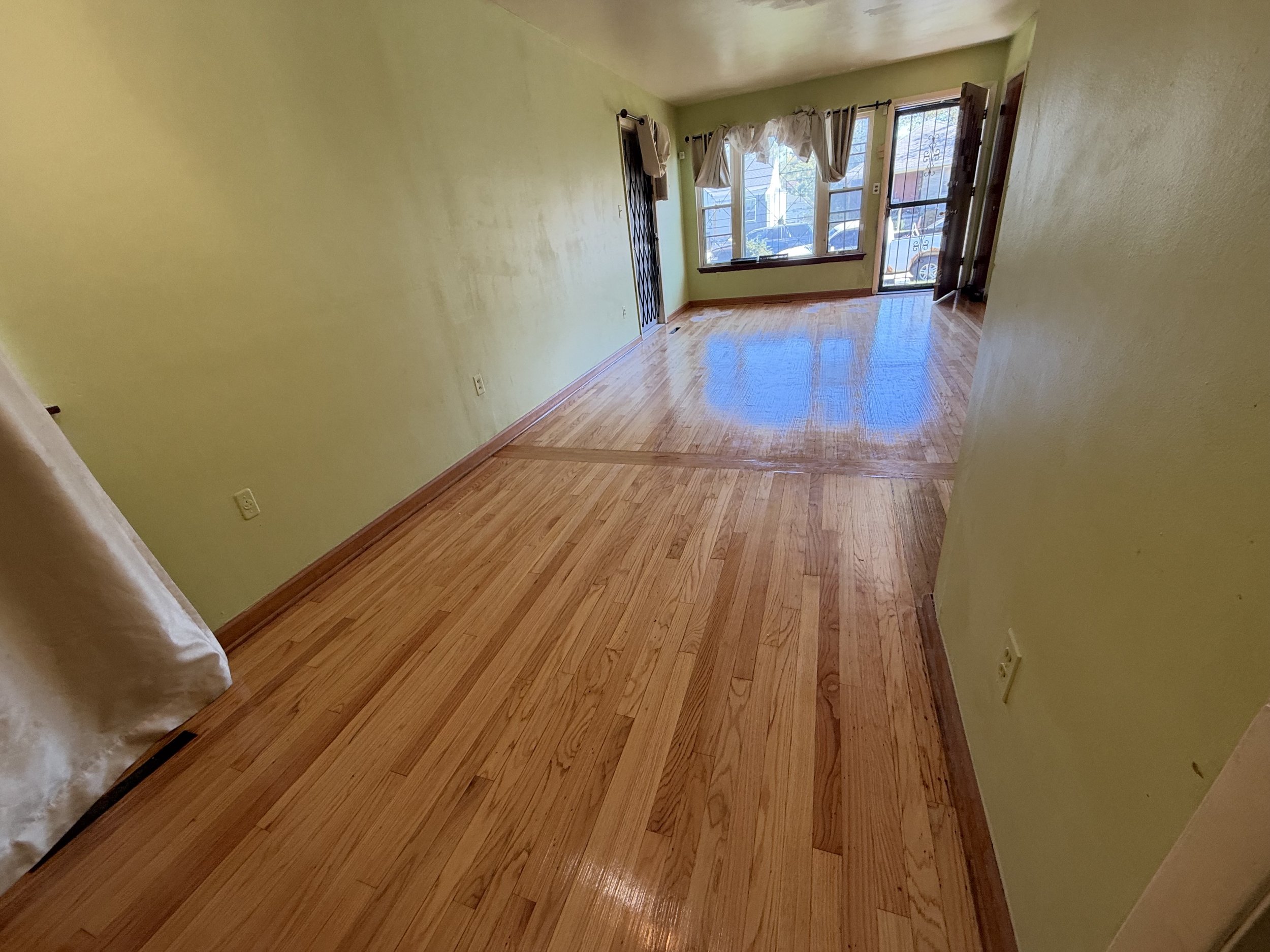 Refinished hardwood flooring with a smooth surface, warm natural color, and lasting clear finish