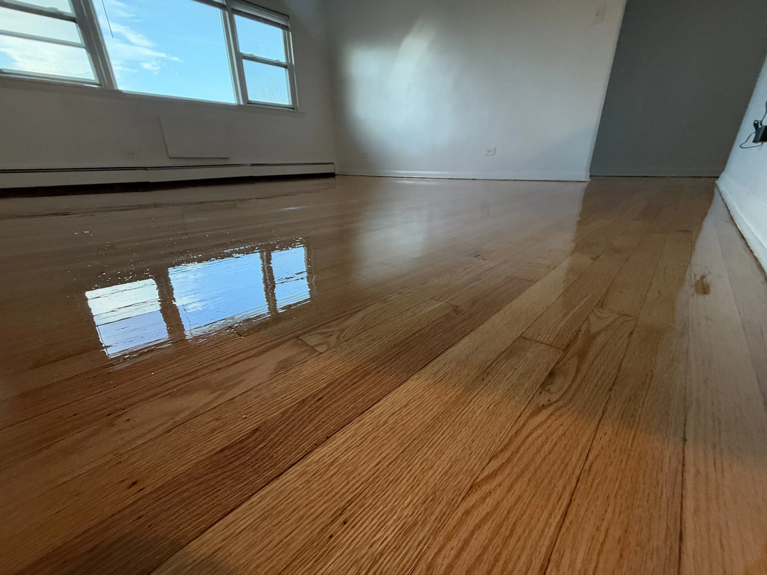 Refinished hardwood floor with a consistent wood tone and protective topcoat in a Streamwood home