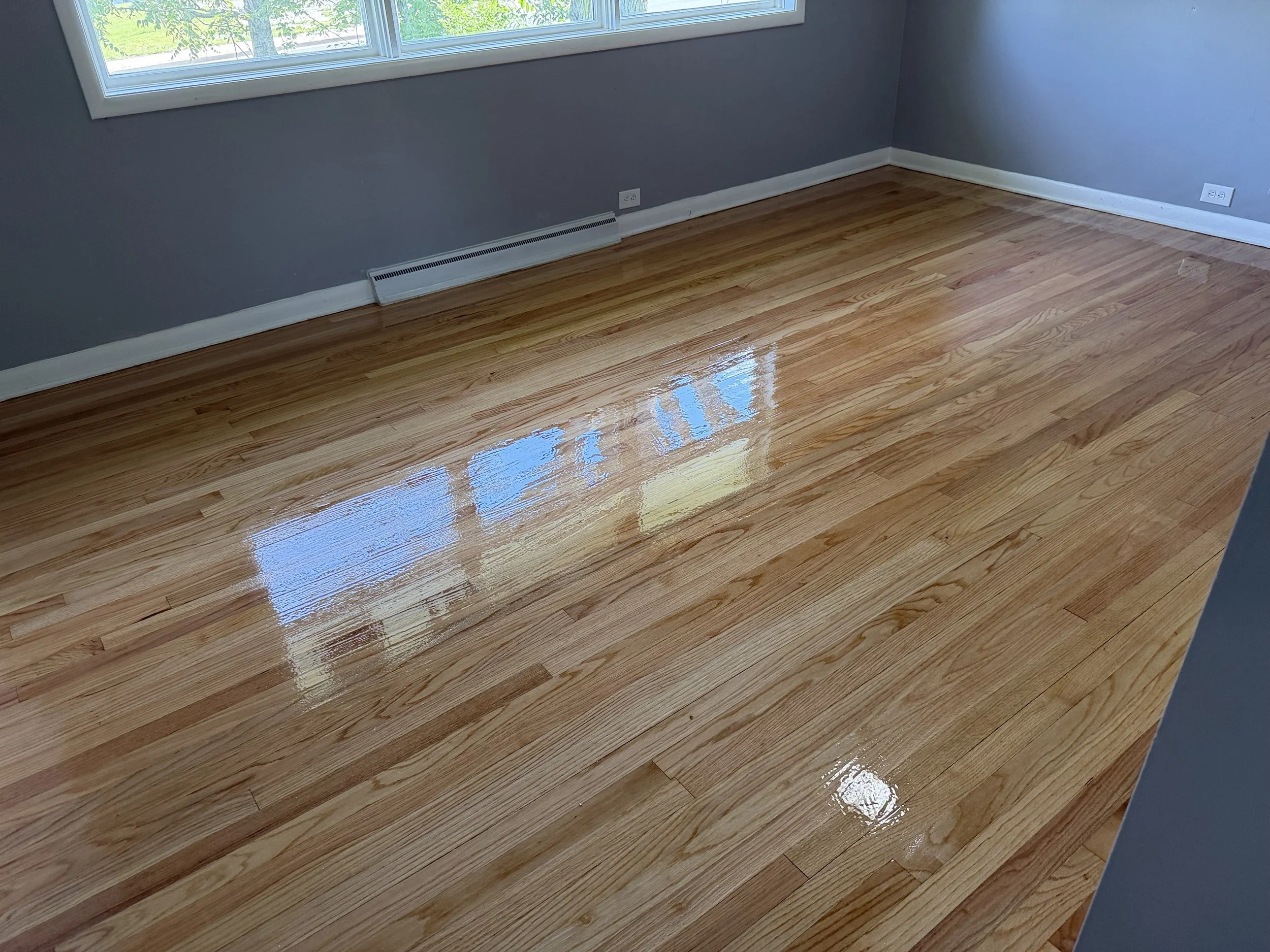Hardwood floor refinished with renewed color and a durable protective coating in a Malta home