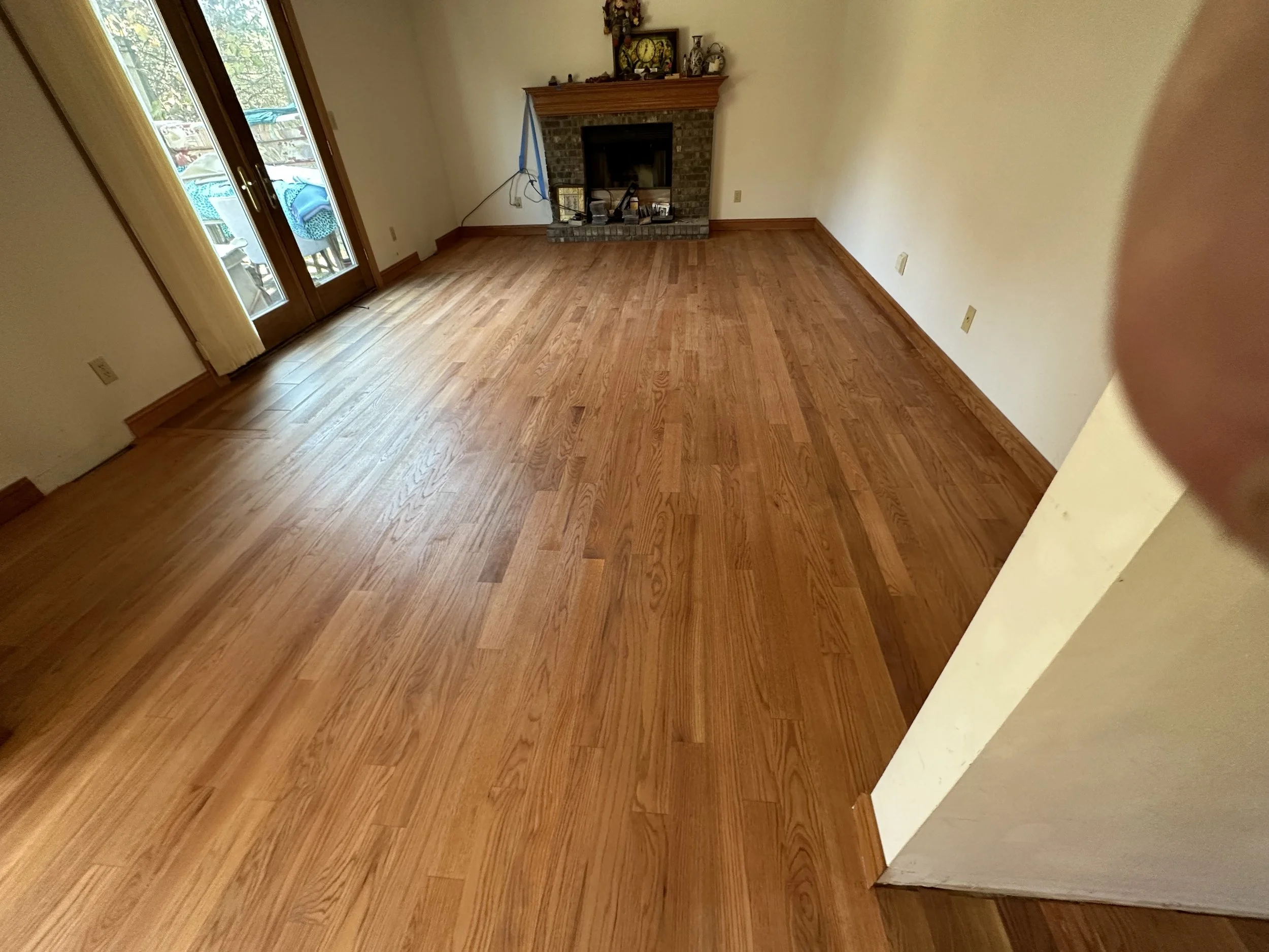 Refinished hardwood floors in a living room with a fireplace