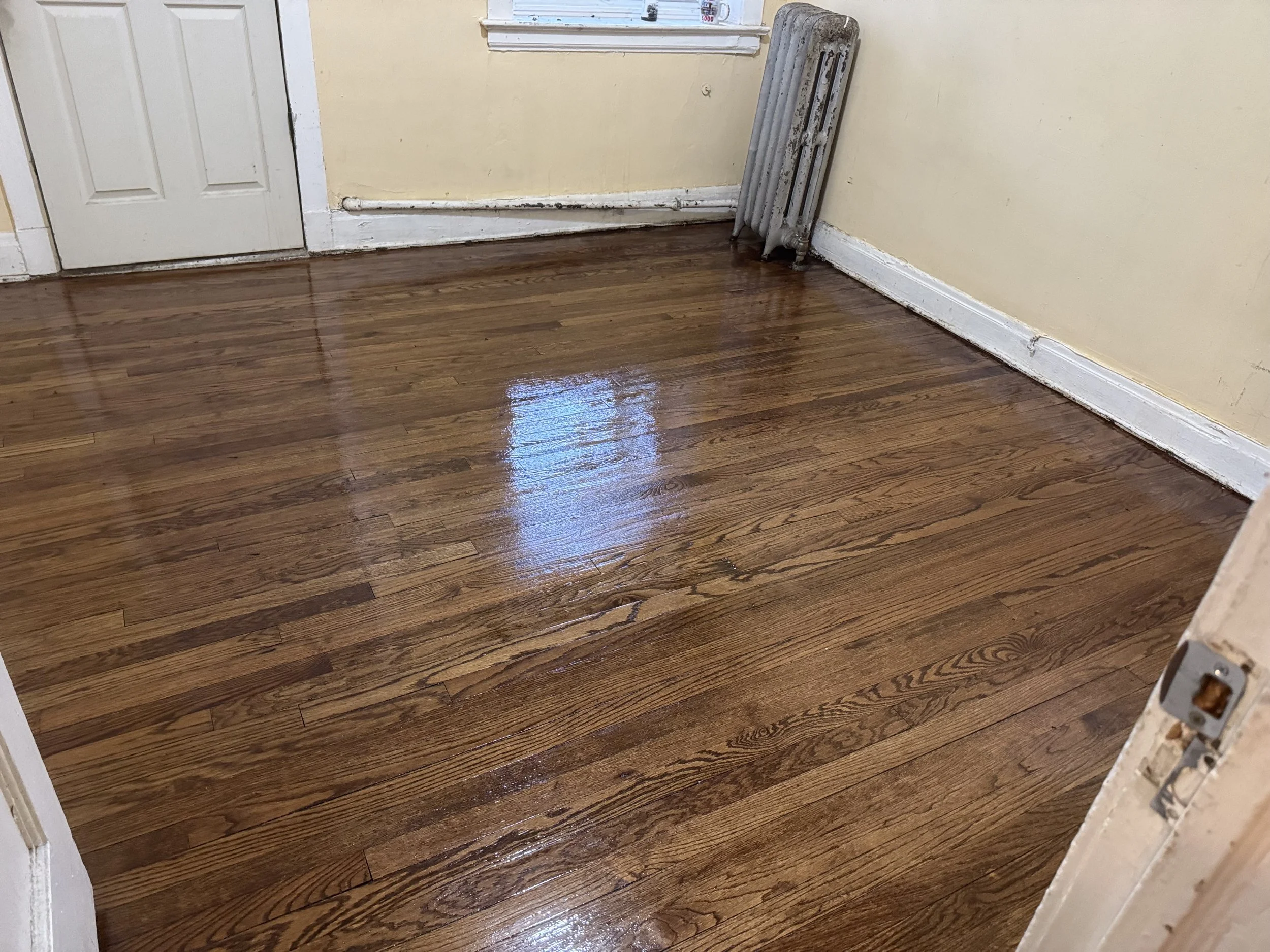 Hardwood floor refinished with renewed smoothness, natural wood color, and a durable protective finish in a Leland home