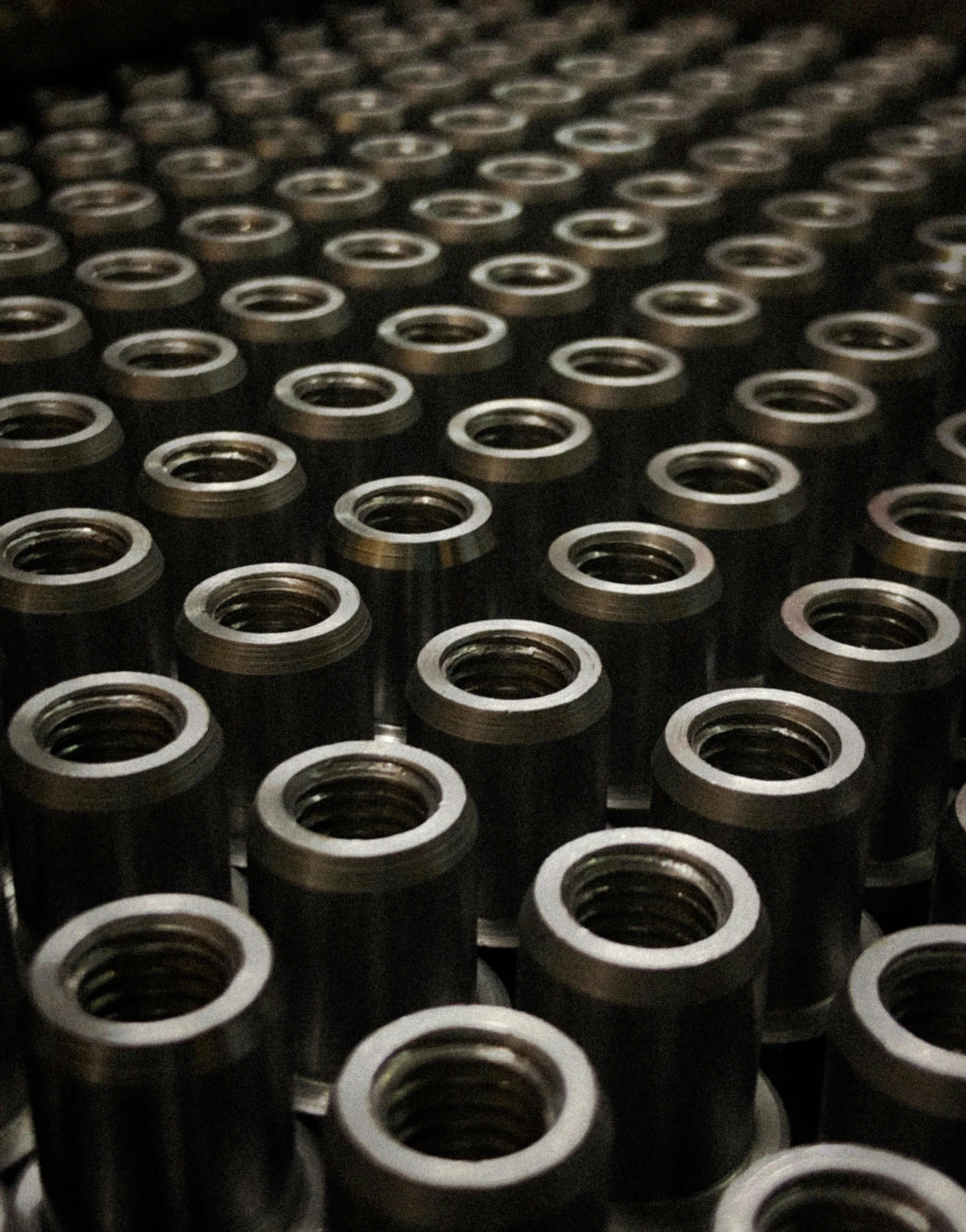 Close-up of multiple black metal mechanical components with circular openings, arranged in a pattern.