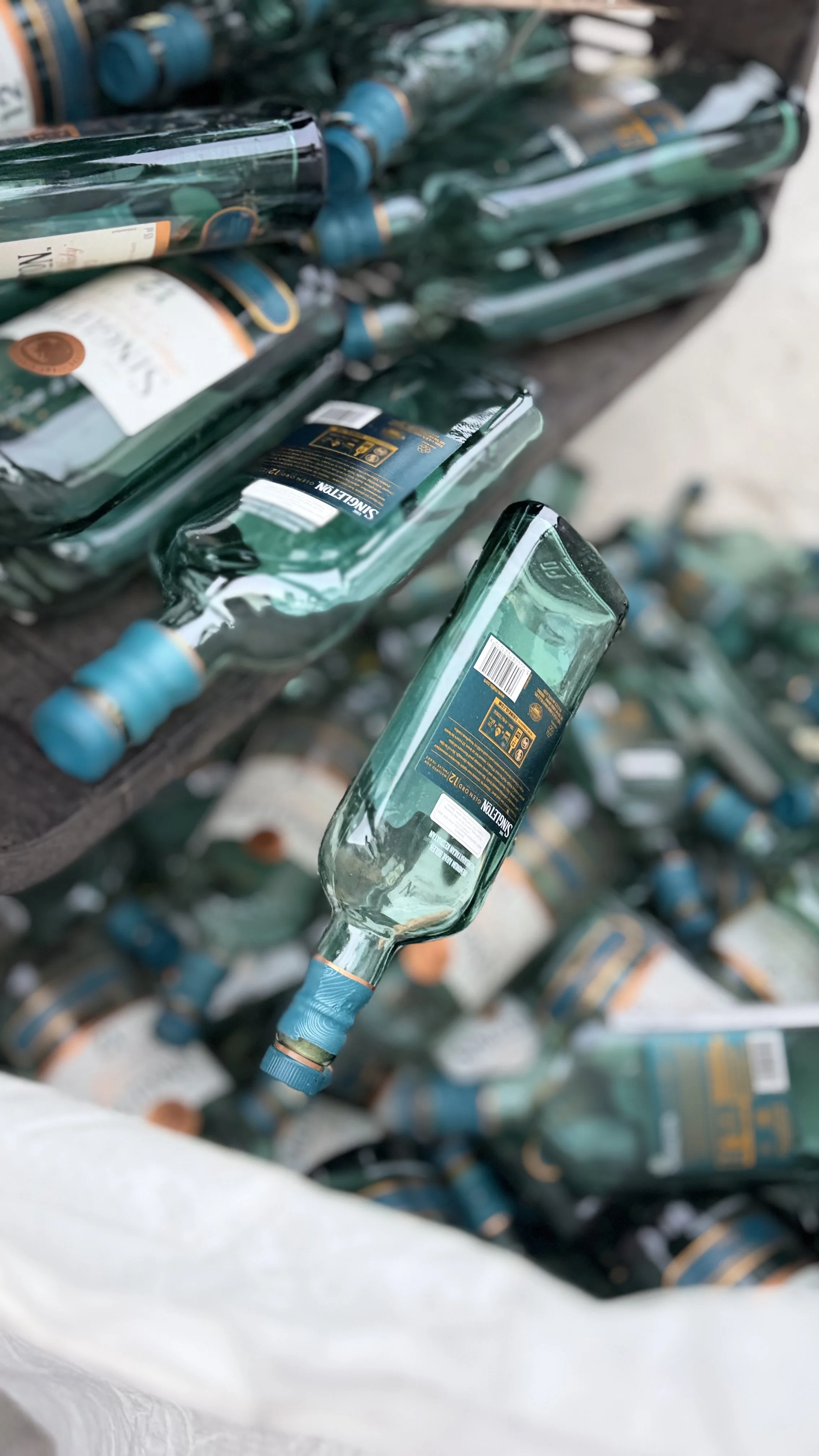 Empty glass bottles of sparkling water with blue caps stacked in a plastic bag.