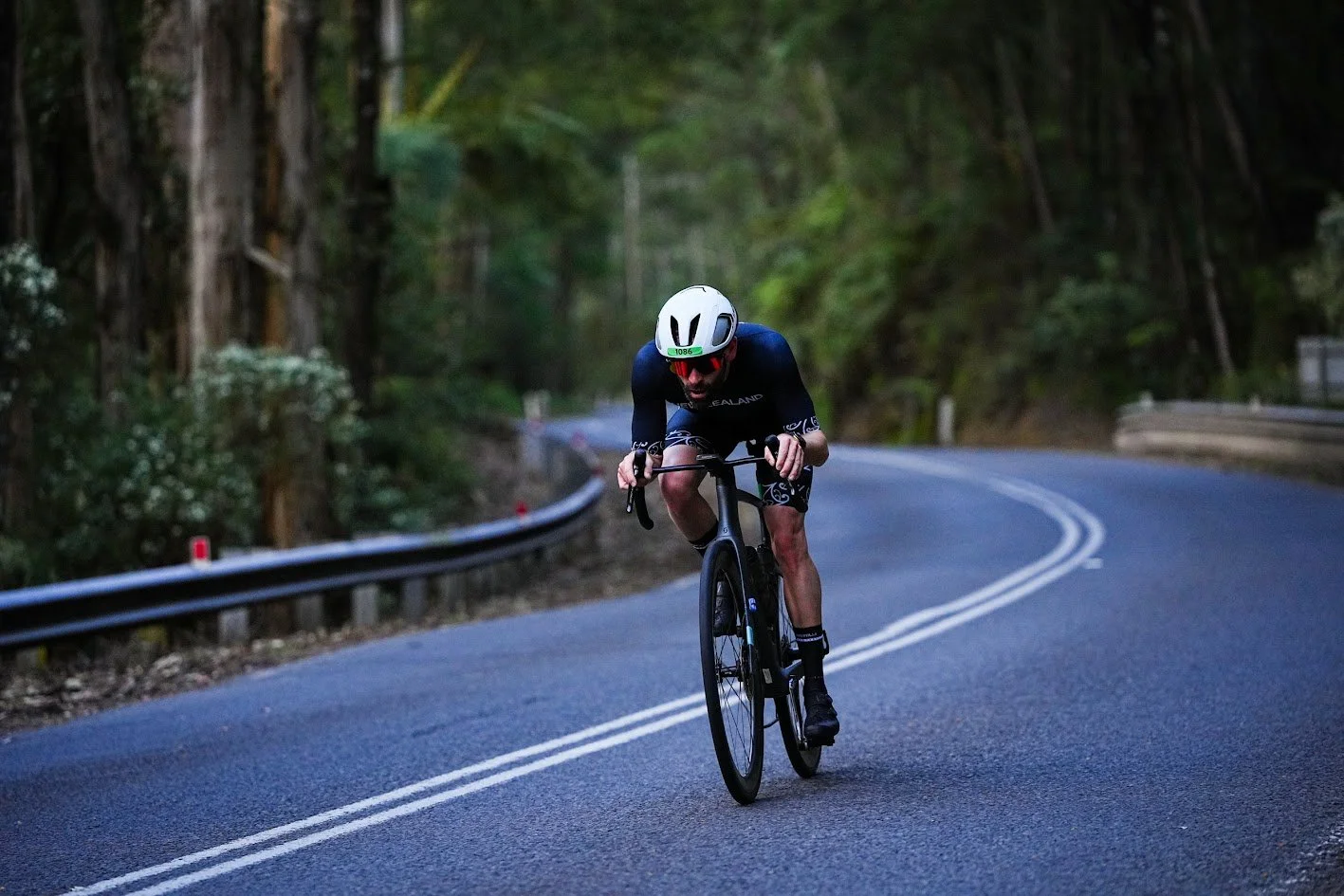 Blair cycling coach competing on a road descent, wearing New Zealand kit