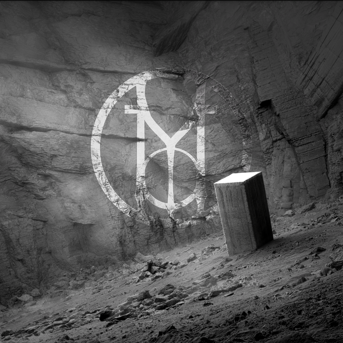 A large, empty, underground quarry or mine with rough stone walls and a dirt floor. There is a rectangular block of stone or concrete standing upright and a faint overlay of a logo with stylized letters."