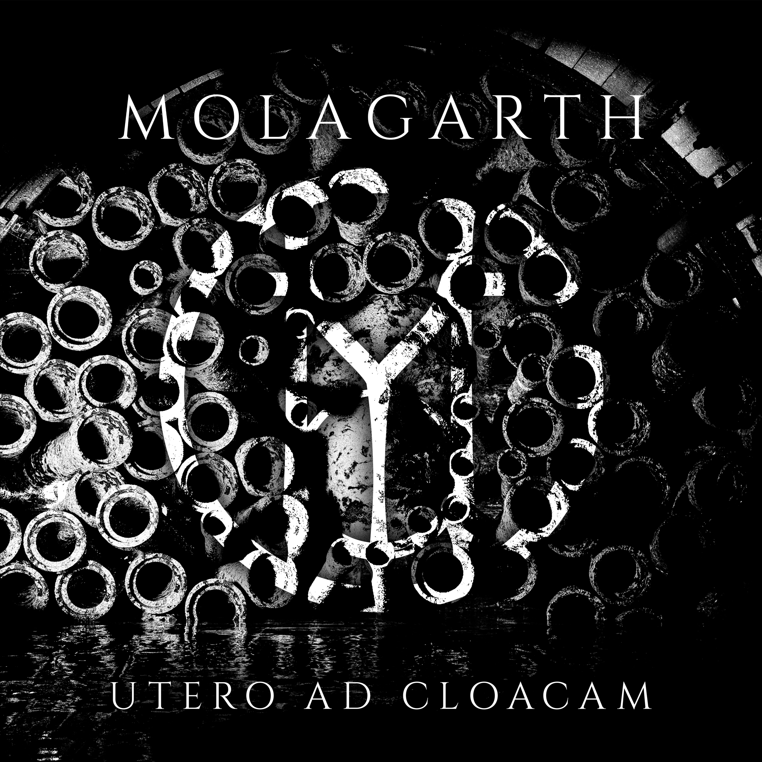 Black and white photo of stacked pipes or tubes, with the word 'MOLAGARTH' at the top, a large unrecognizable symbol in the middle, and the phrase 'ÚTERO AD CLOACAM' at the bottom.