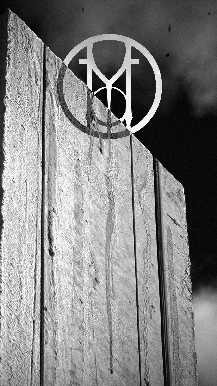 Black and white photo of aMonument with a dark sky background, featuring the Molagarth emblem overlayed in the center.