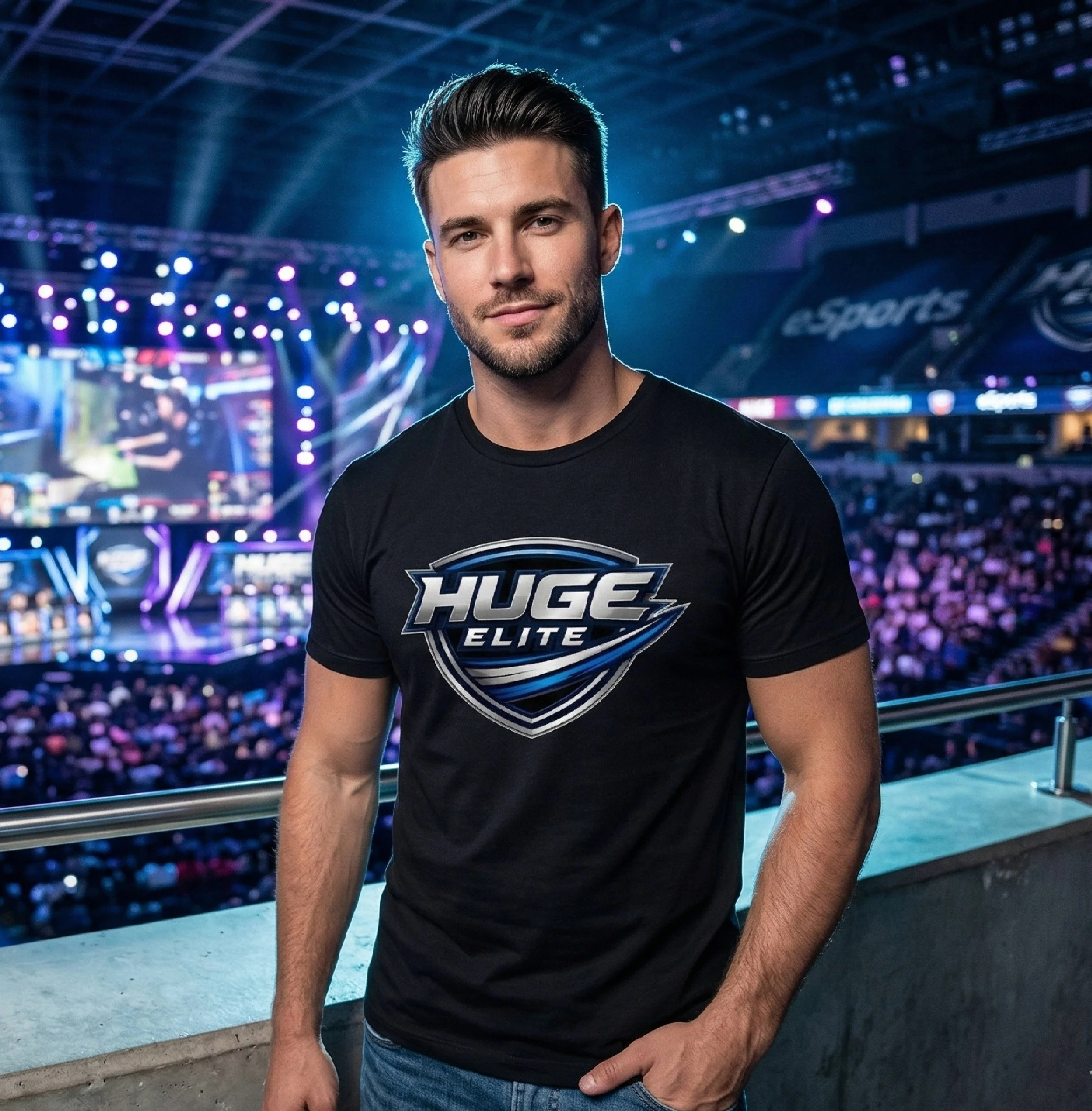 A young man with dark hair and a beard, wearing a black T-shirt with the words 'HUGE ELITE' on it, sitting at a sports arena with vibrant purple, blue, and yellow lights in the background.