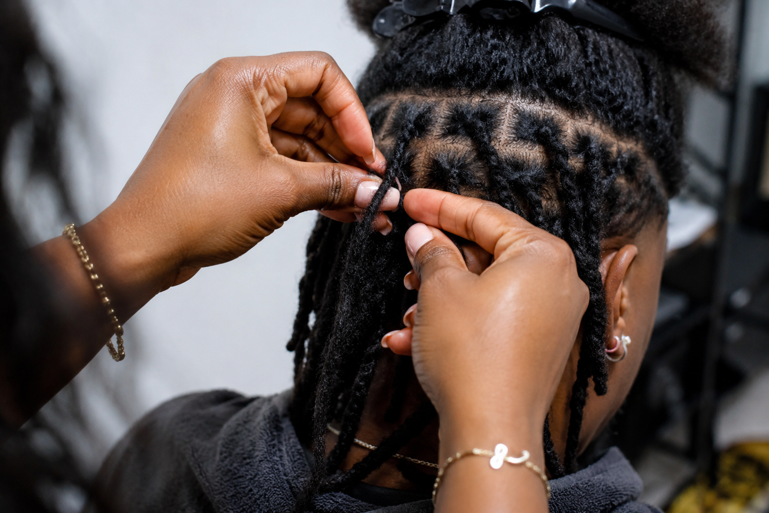 Person with dreadlocks getting a hair braid or twist done by a hairstylist.