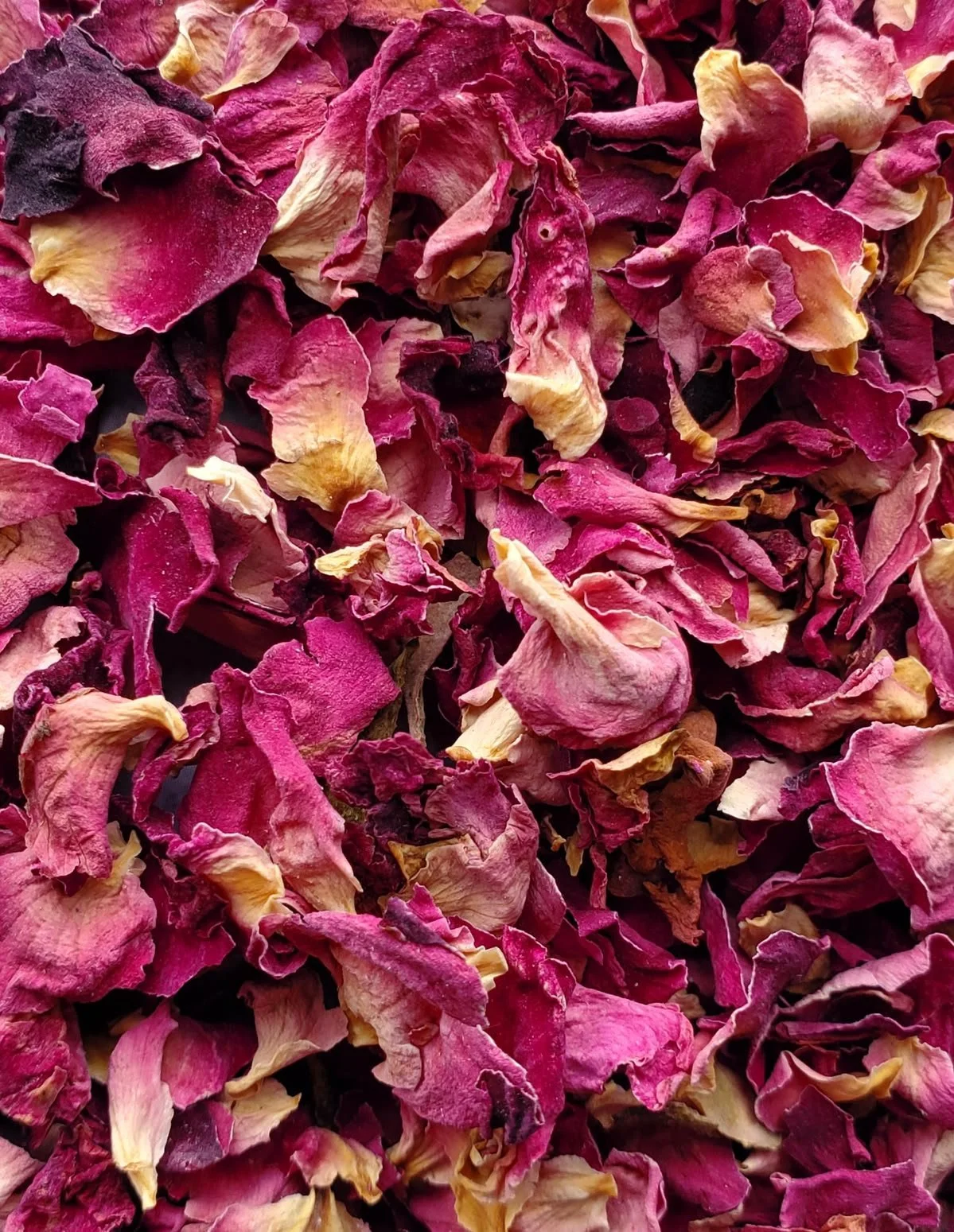 Dried rose petals in shades of pink, purple, and cream.