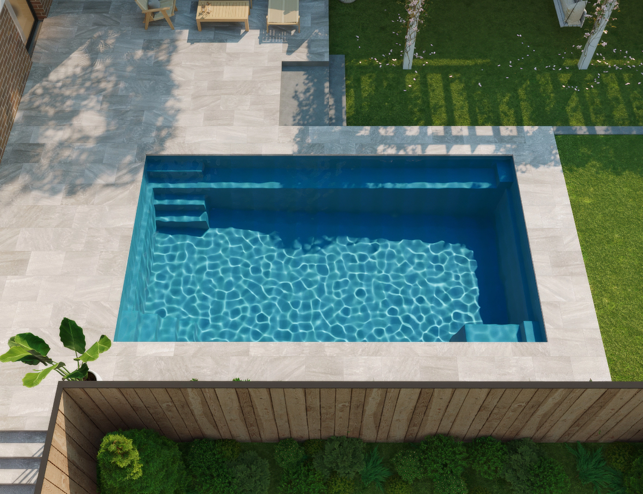 A backyard with a rectangular swimming pool, stone patio, wooden chairs, and green grass with trees.