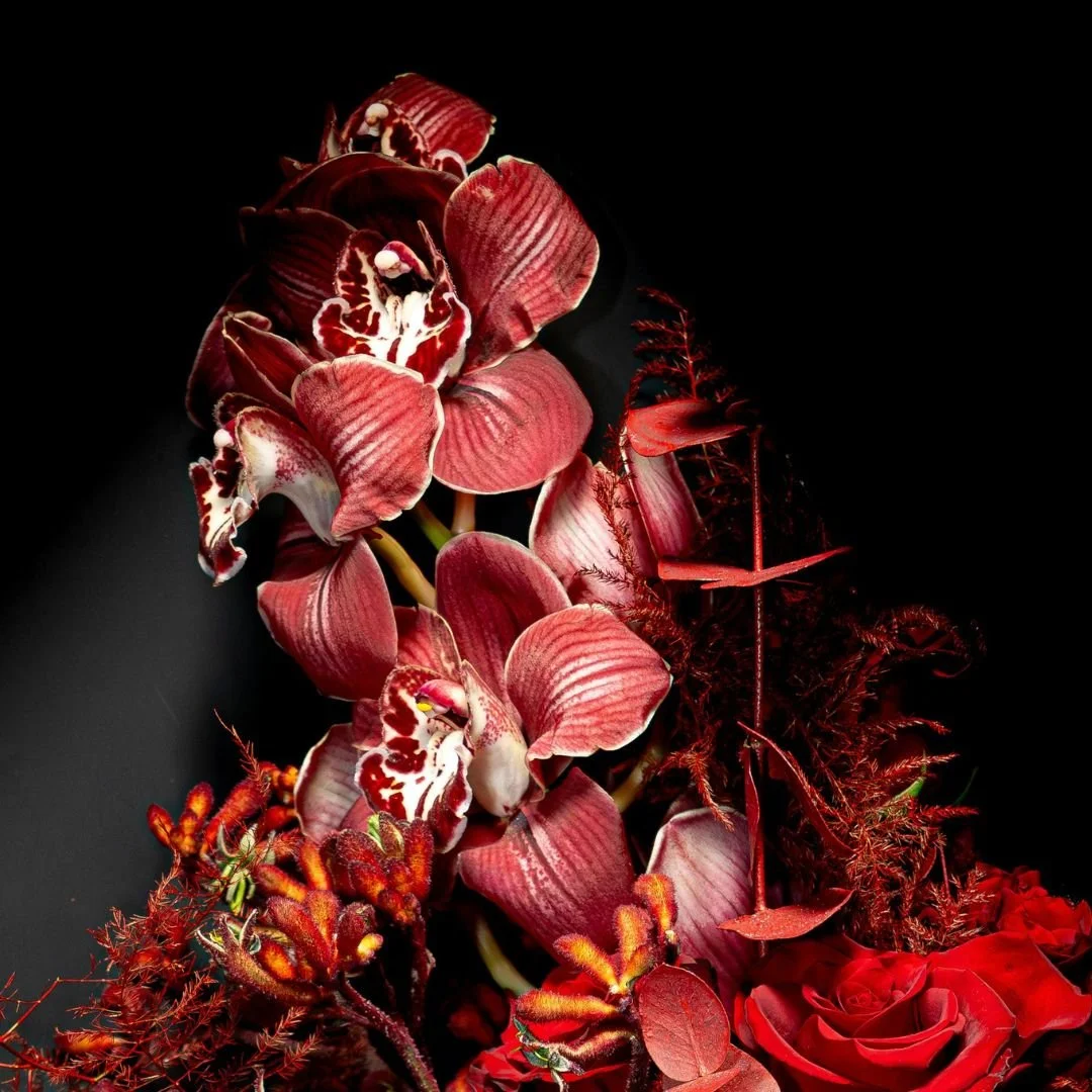 close up of red orchids and other red-hued flowers in a bouquet arrangement