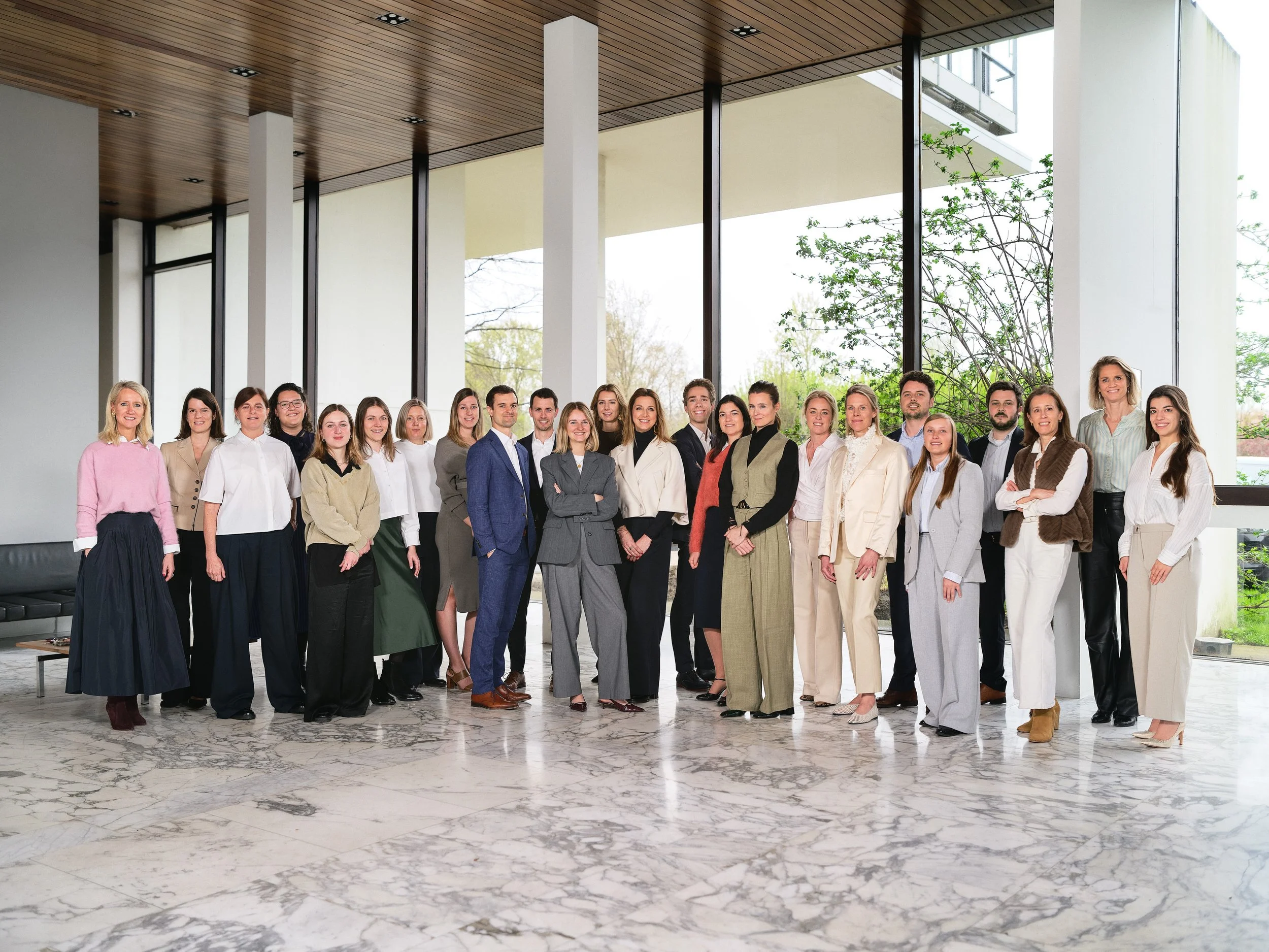 Group of diverse professionals standing together in a modern, spacious office lobby with large windows and marble flooring.