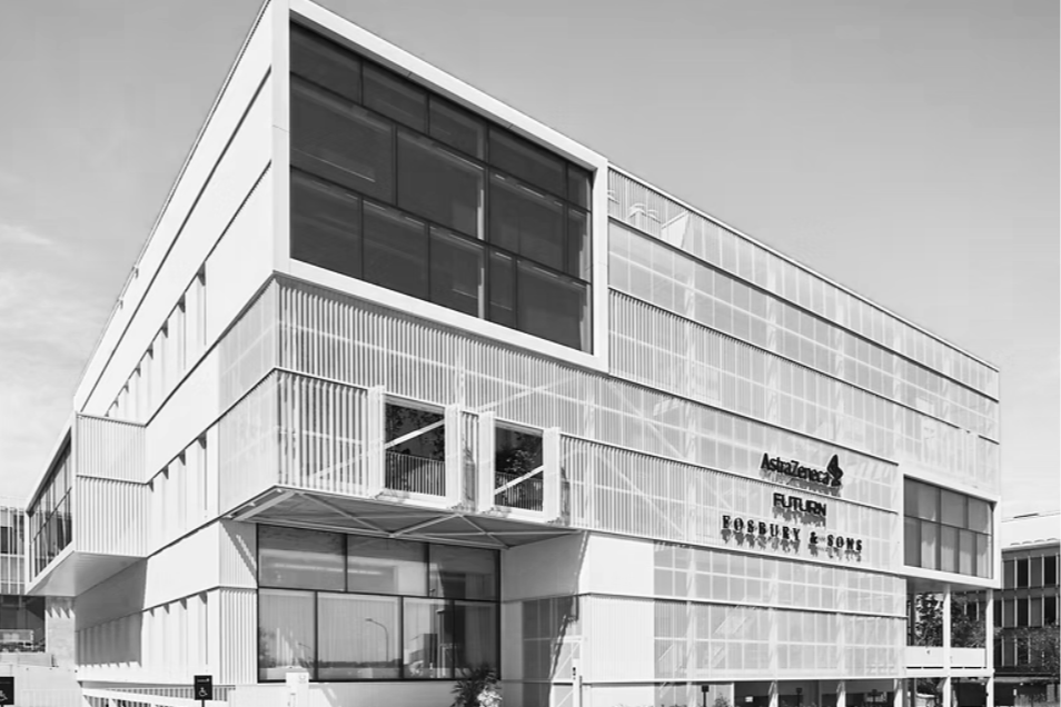 Modern multi-story office building with glass windows and metal framework, featuring signage for AstraZeneca, Fulcrum, and Gossbury & Sons.