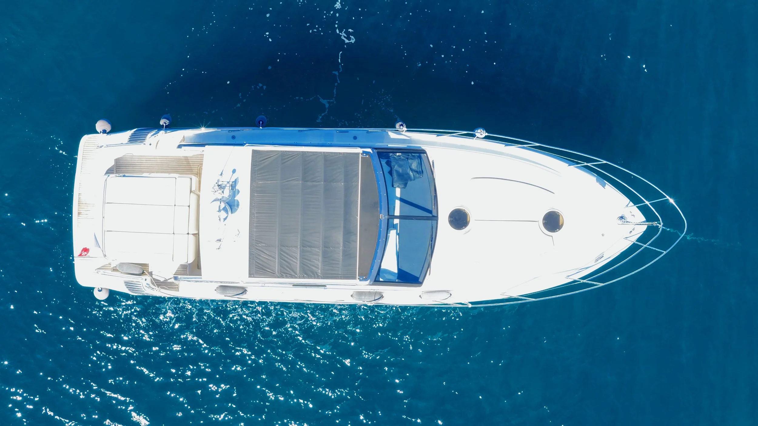 Aerial view of a white yacht sailing on the ocean, with blue water surrounding it.