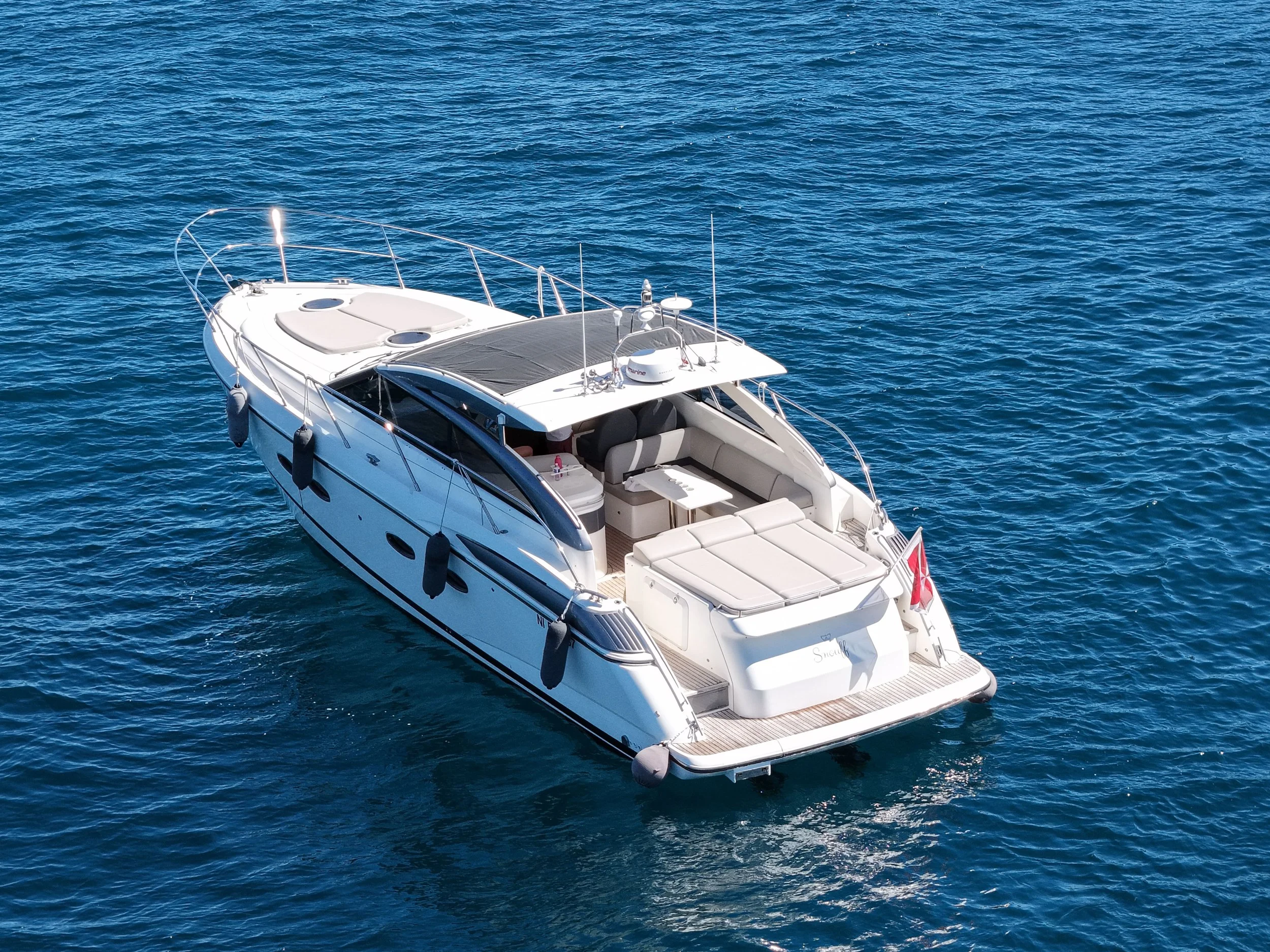 Large white luxury yacht floating on blue ocean water, with open deck areas and seating.