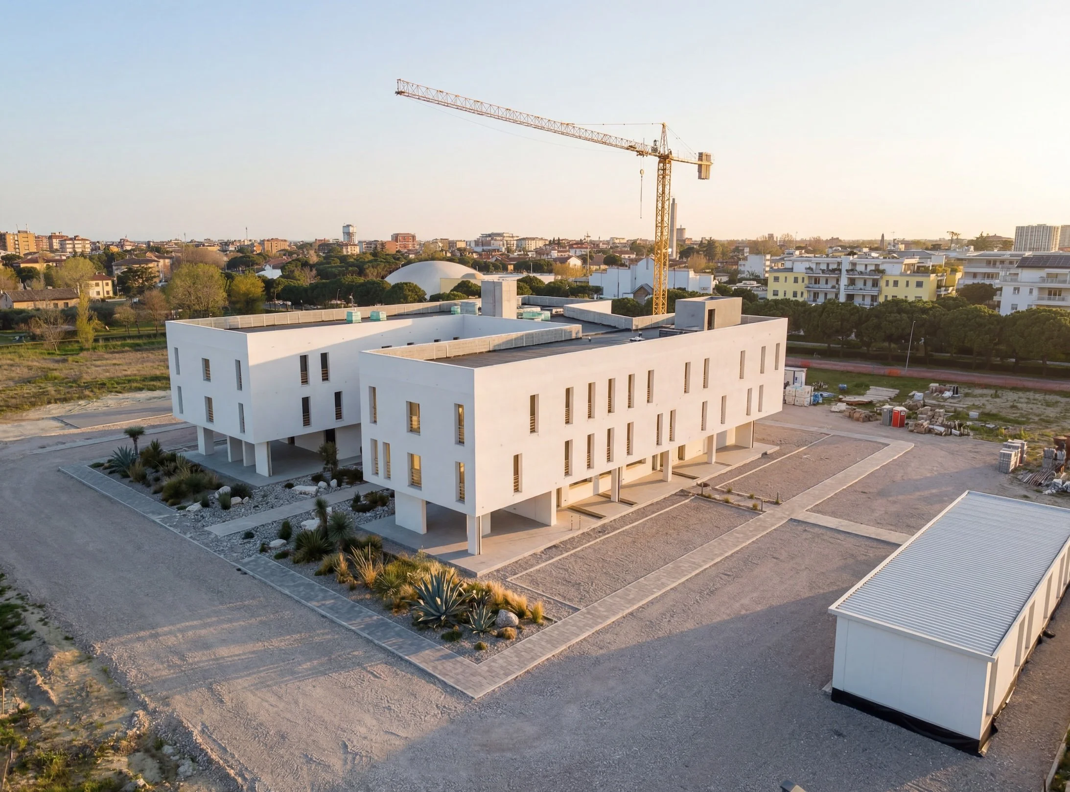 Immagine di un edificio bianco moderno sotto un cielo sereno con un cantiere con gru in background. Ospedale di Ravenna