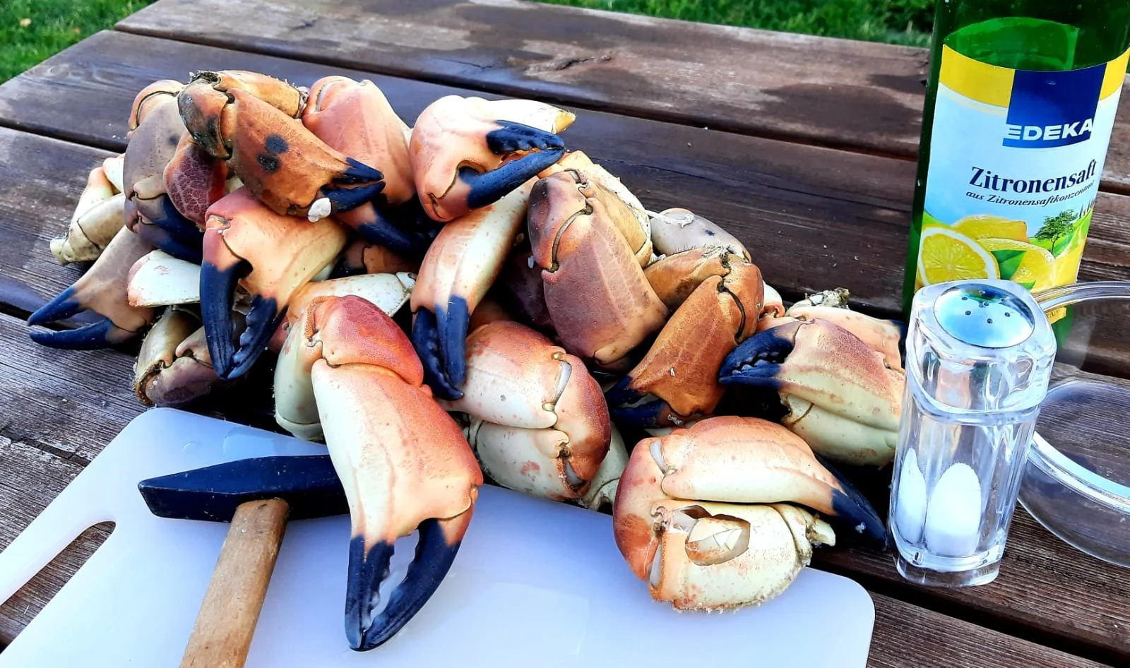 Frische Miesmuscheln auf einem Schneidebrett, daneben Zitronensaft und Salz.