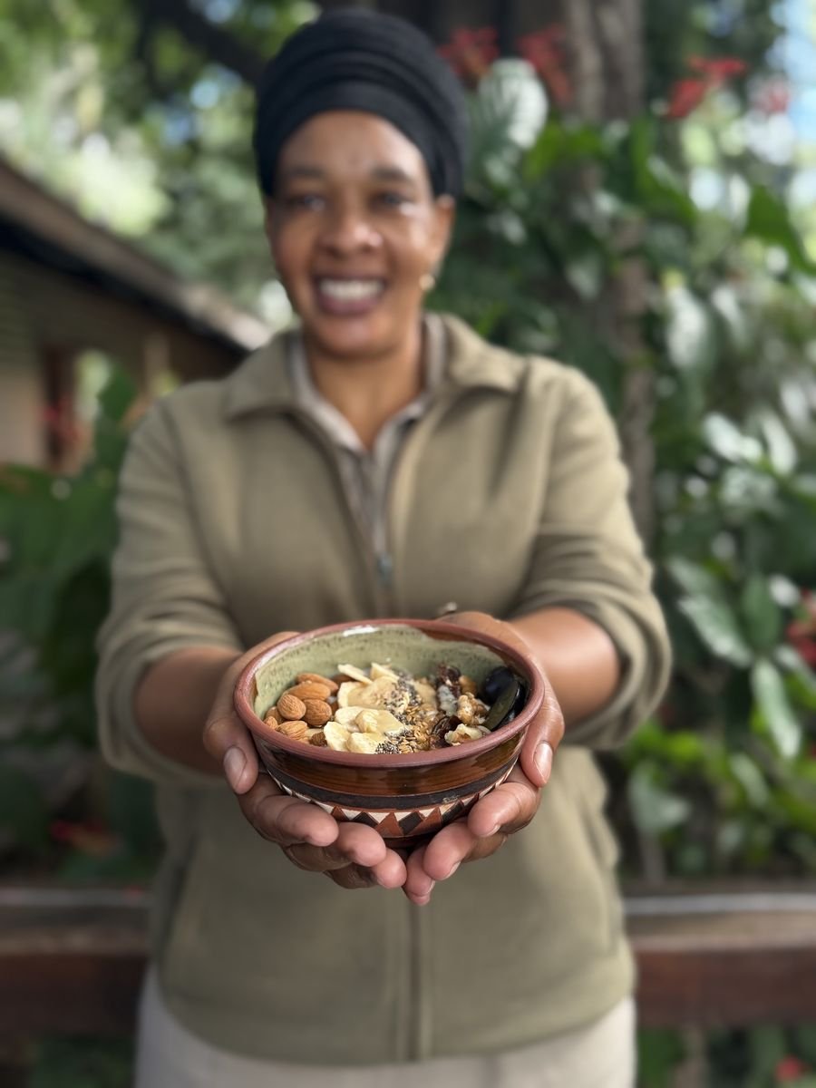 A local woman smiling and holding a healthy breakfast bowl in a lush surrounding in the Delta.