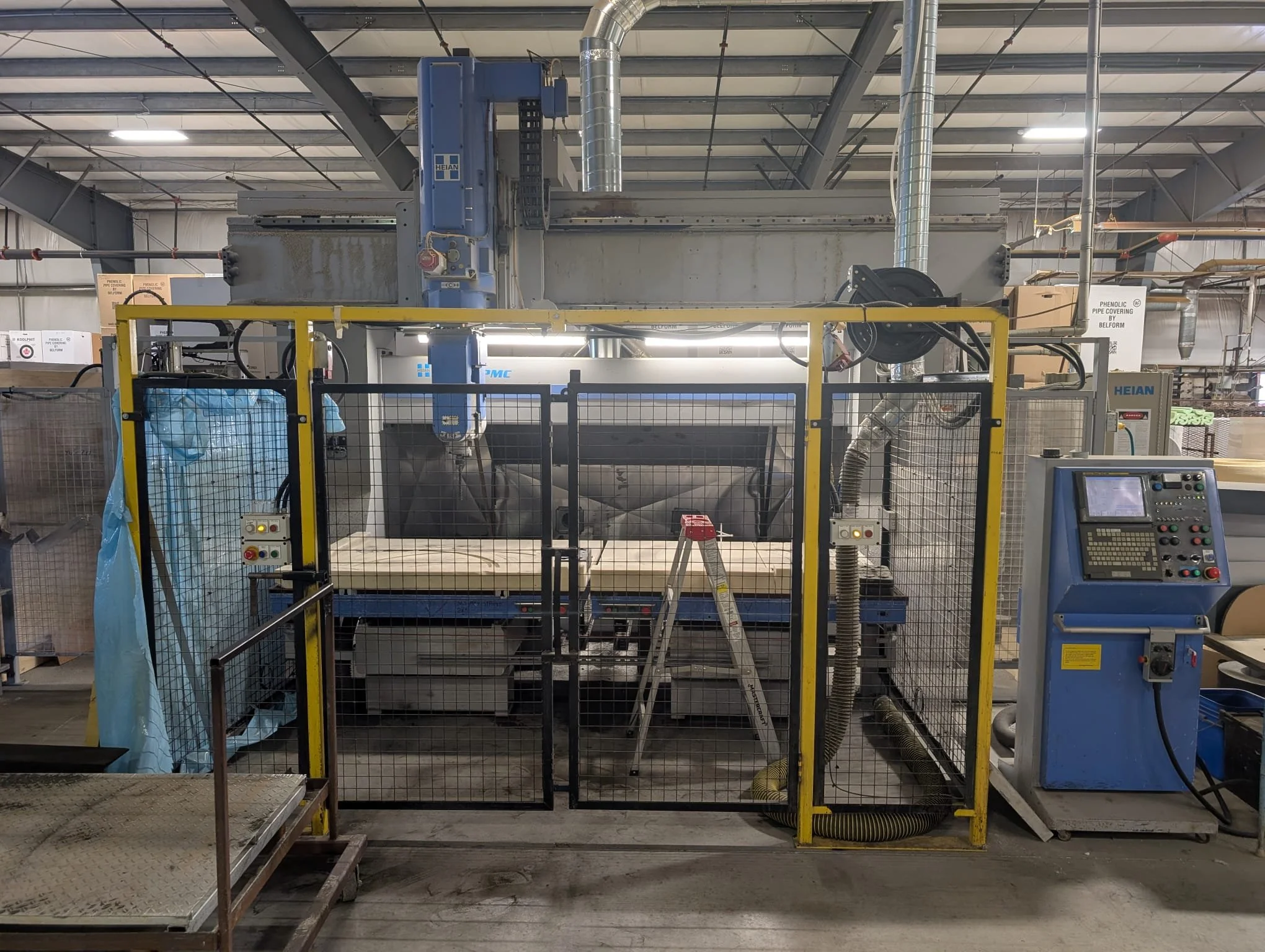 Industrial manufacturing facility with machinery and equipment, including pipes, control panels, and safety barriers.