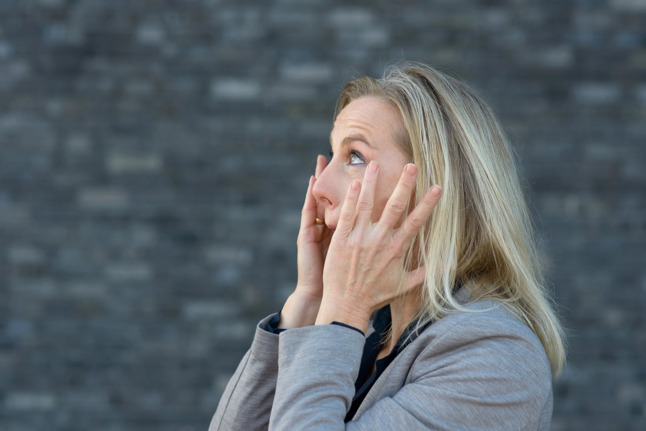 A woman with blonde hair talking on a cellphone outdoors.