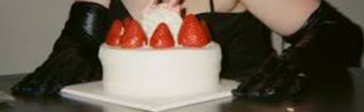 High class sex work escort Celine Syn sits with cake in long black latex gloves. Kinky London Escort Celine at a party with beautiful creamy strawberry cake. London BDSM dom Celine. Date a sex worker, educated intelligent kind in London