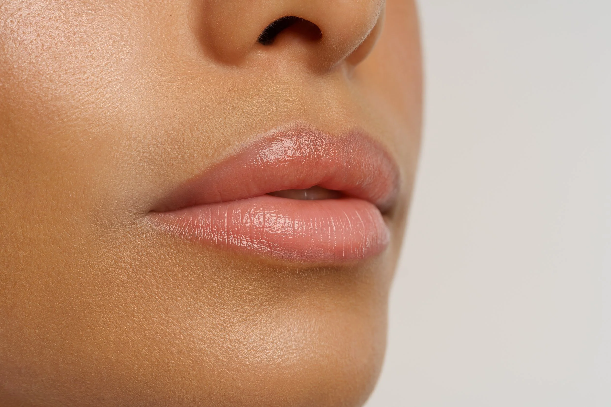 Close-up of a person's face focusing on the nose and lips, with smooth skin and lips slightly parted.
