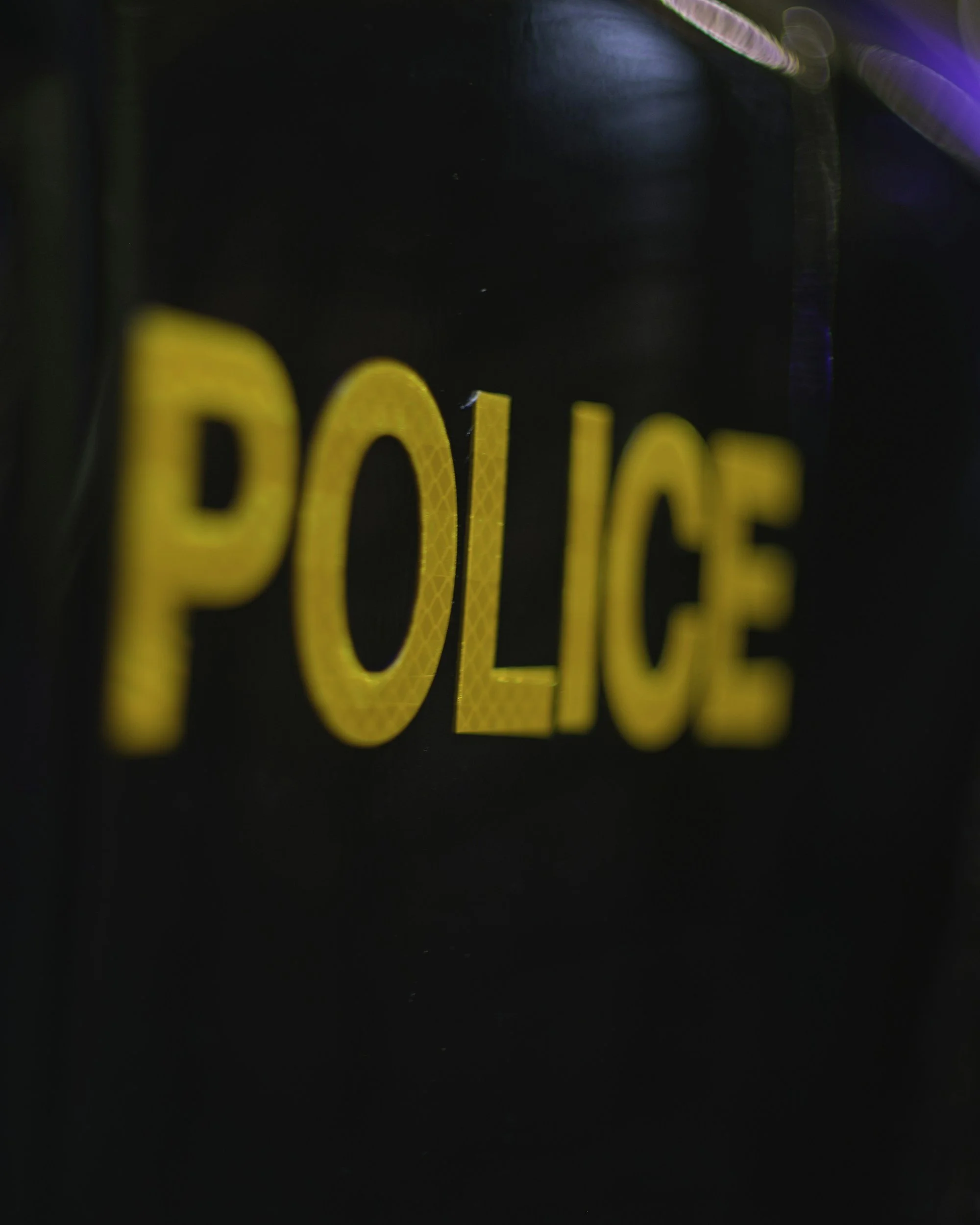 Close-up of a police badge with the word 'POLICE' in yellow letters on a black background.