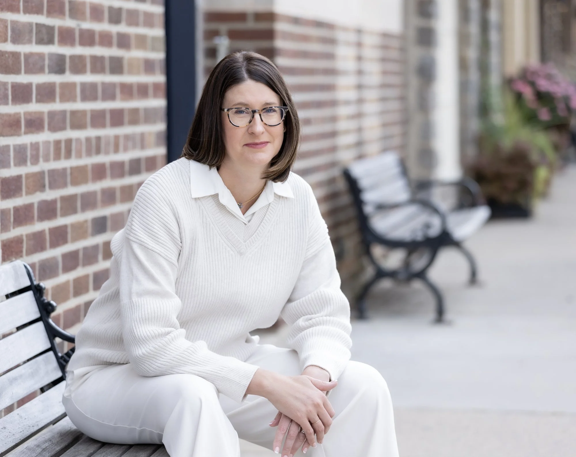 Jill Decker, LPCC, seated on a bench outside a brick building